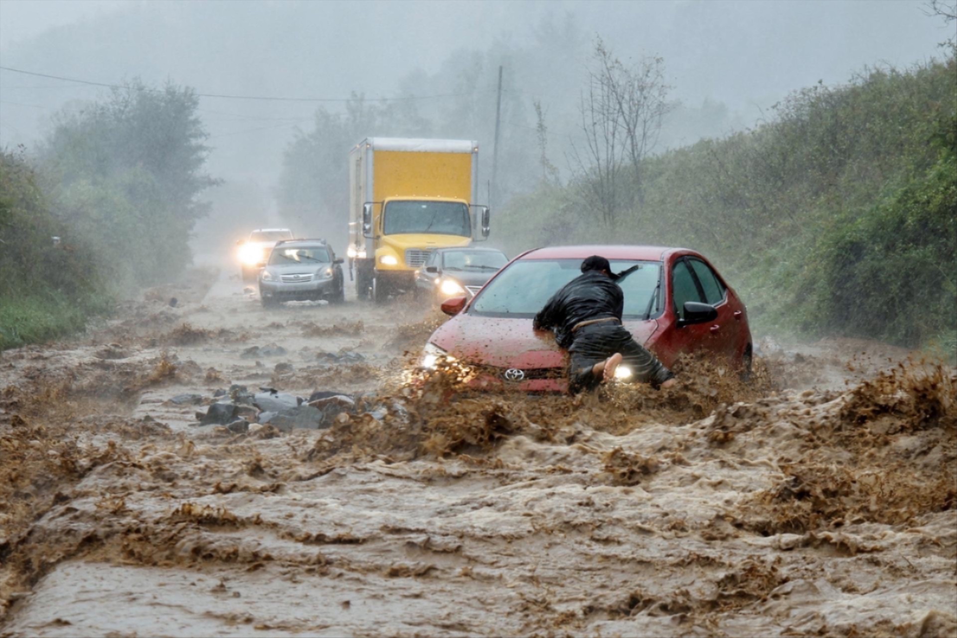 A local resident helps free a car that became stranded in a stretch of flooding road as Tropical Storm Helene strikes, on the outskirts of Boone, North Carolina, U.S. September 27, 2024. 