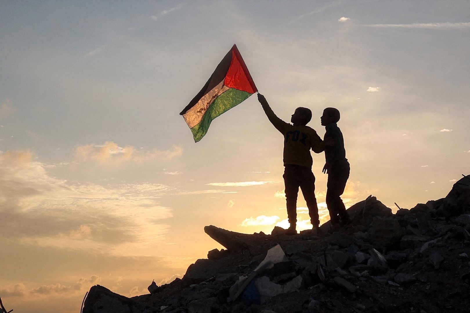 A boy holds a Palestinian flag on top of a mound of rubble in the central Gaza Strip.