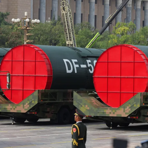 Two DF-5C nuclear missiles are displayed during a military parade as soldiers stand guard.