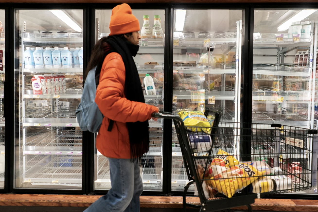 A shopper walks past a partially empty dairy section at a grocery store ahead of an expected winter storm spreading across the United States, in Washington, D.C., U.S., January 24, 2026. REUTERS/Nathan Howard/File Photo