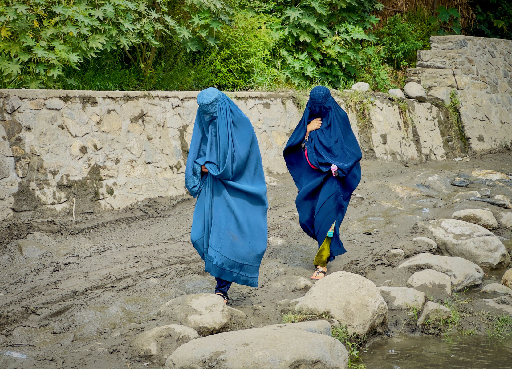 Afghan women in burqa walk towards a safer place after their house was damaged following a deadly magnitude 6 earthquake that struck Afghanistan on Sunday, at Lulam village, in Nurgal district, Kunar province, Afghanistan, September 3, 2025