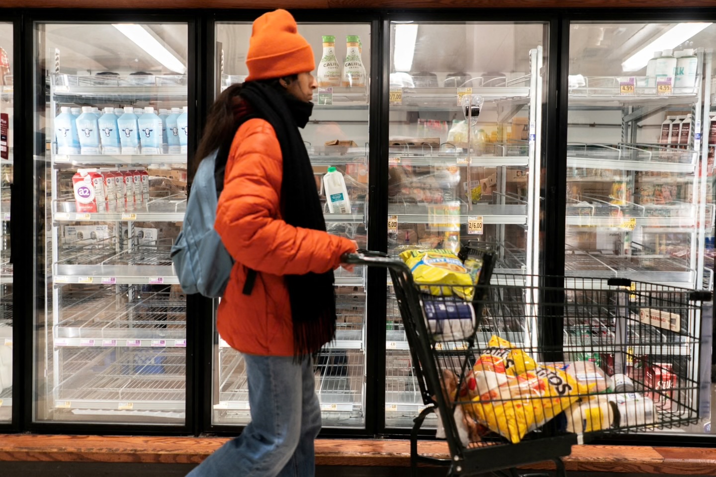 A shopper walks past a partially empty dairy section at a grocery store ahead of an expected winter storm spreading across the United States, in Washington, D.C., U.S., January 24, 2026. 