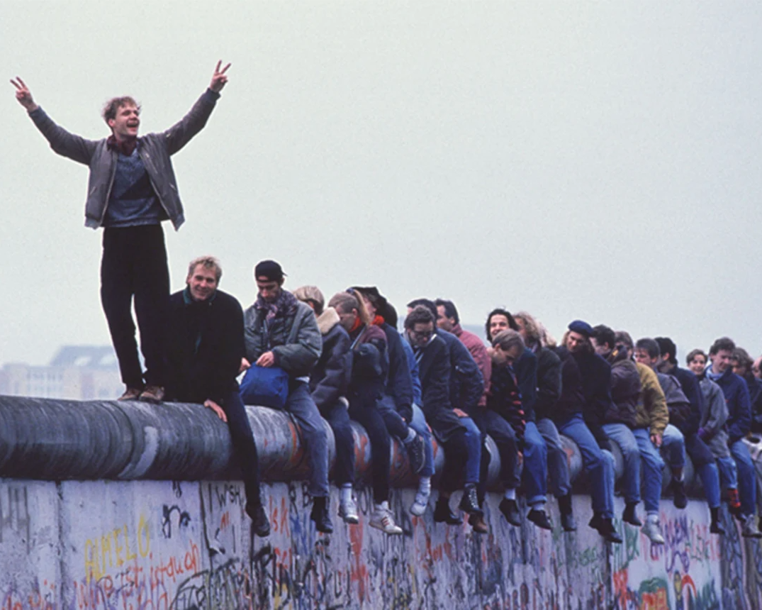 West Germans celebrate the unification of Berlin atop the Berlin Wall during the collapse of communism in East Berlin on November 12, 1989. 