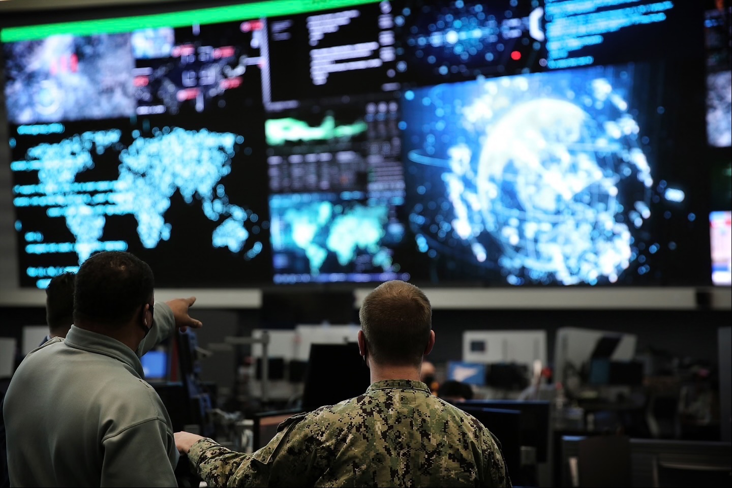 Two officials at U.S. Cyber Command, headquartered in Fort George G. Meade, Maryland, examine a row of screens at their workplace.