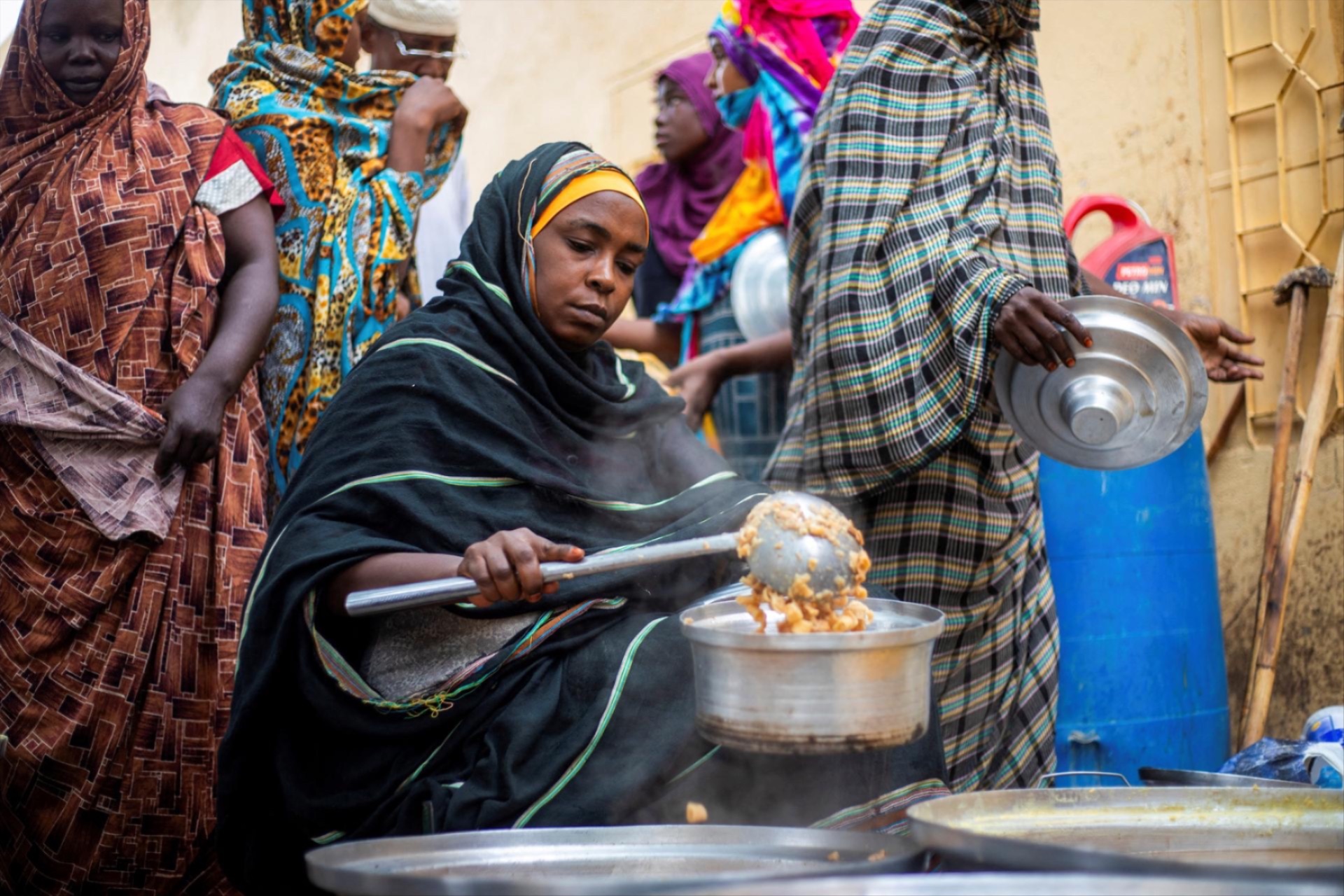 A Sudanese woman from a community kitchen run by local volunteers distributes meals for people who are affected by conflict and extreme hunger and are out of reach of international aid efforts, in Omdurman, Sudan, August 22, 2024. 