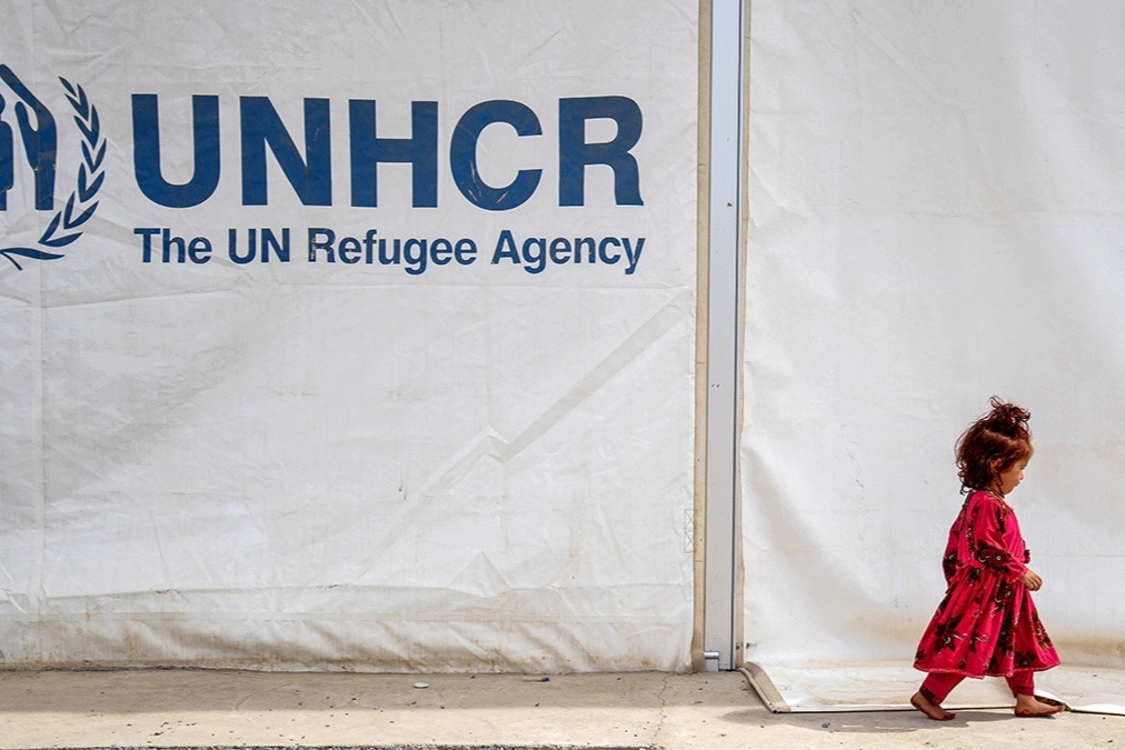 An Afghan refugee girl walks past a registration centre with the United Nations High Commissioner for Refugees (UNHCR) signage, at the Takhta Pul district in Kandahar province on April 7, 2025, upon her arrival from Pakistan.