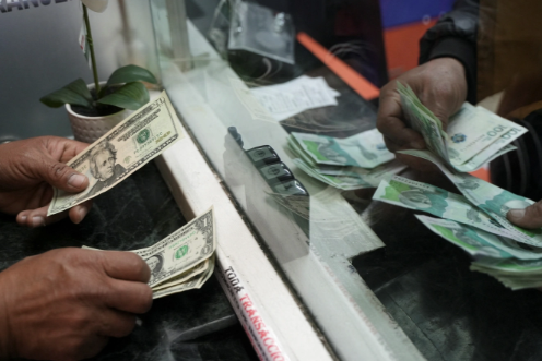 A person exchanges U.S. dollars for Colombian pesos at a currency exchange house in Bogota, Colombia, on June 10. Nathalia Angarita/Reuters