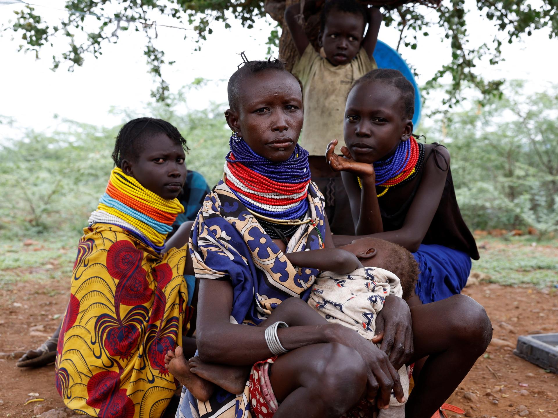 Turkana women sit under a tree as community health workers screen their children for malnutrition, in Aposta village, Turkana County, Kenya, on October 30, 2025.