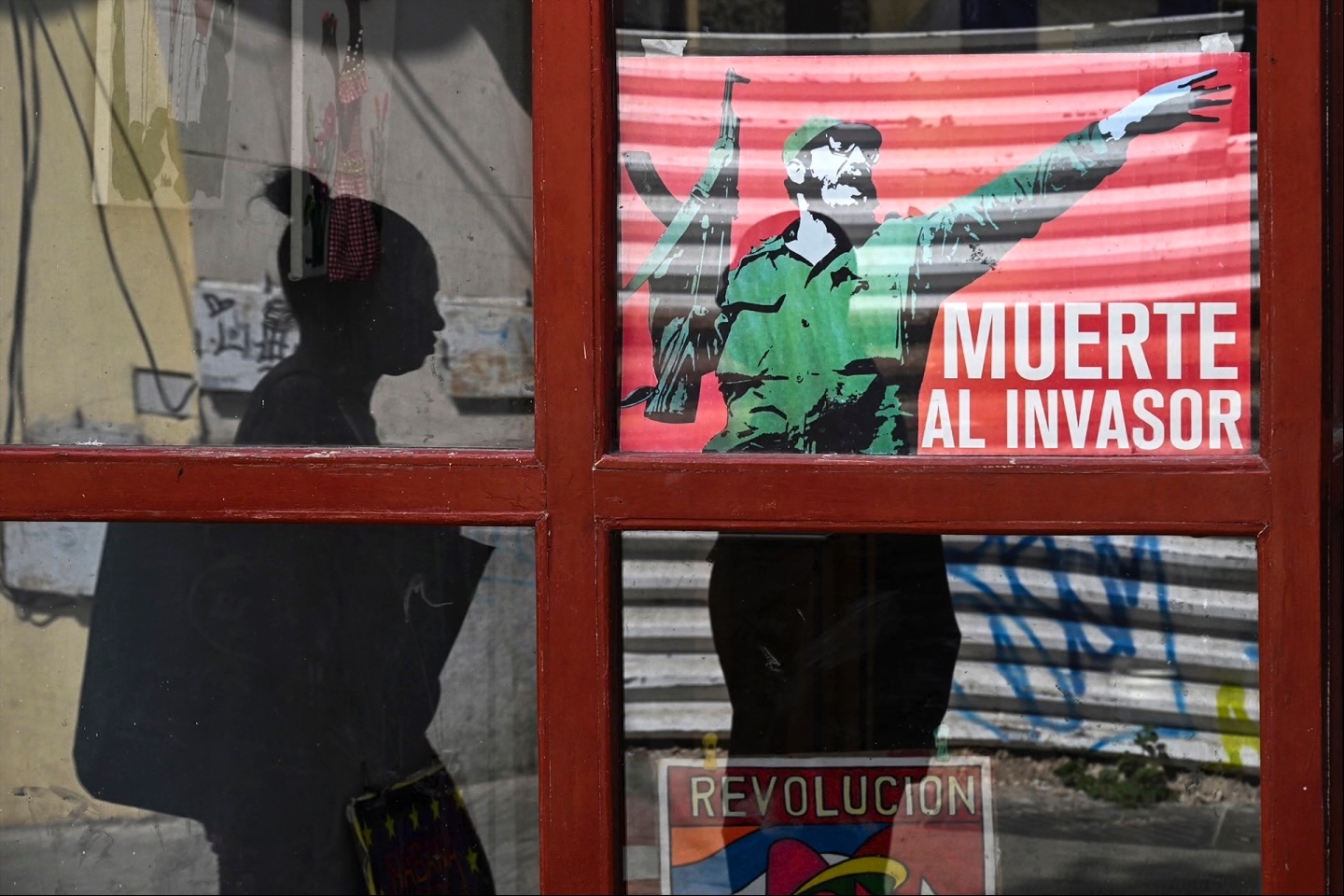 A woman walks past a poster of late Cuban leader Fidel Castro reading, “Death to the invader” in Havana, on March 13, 2026.