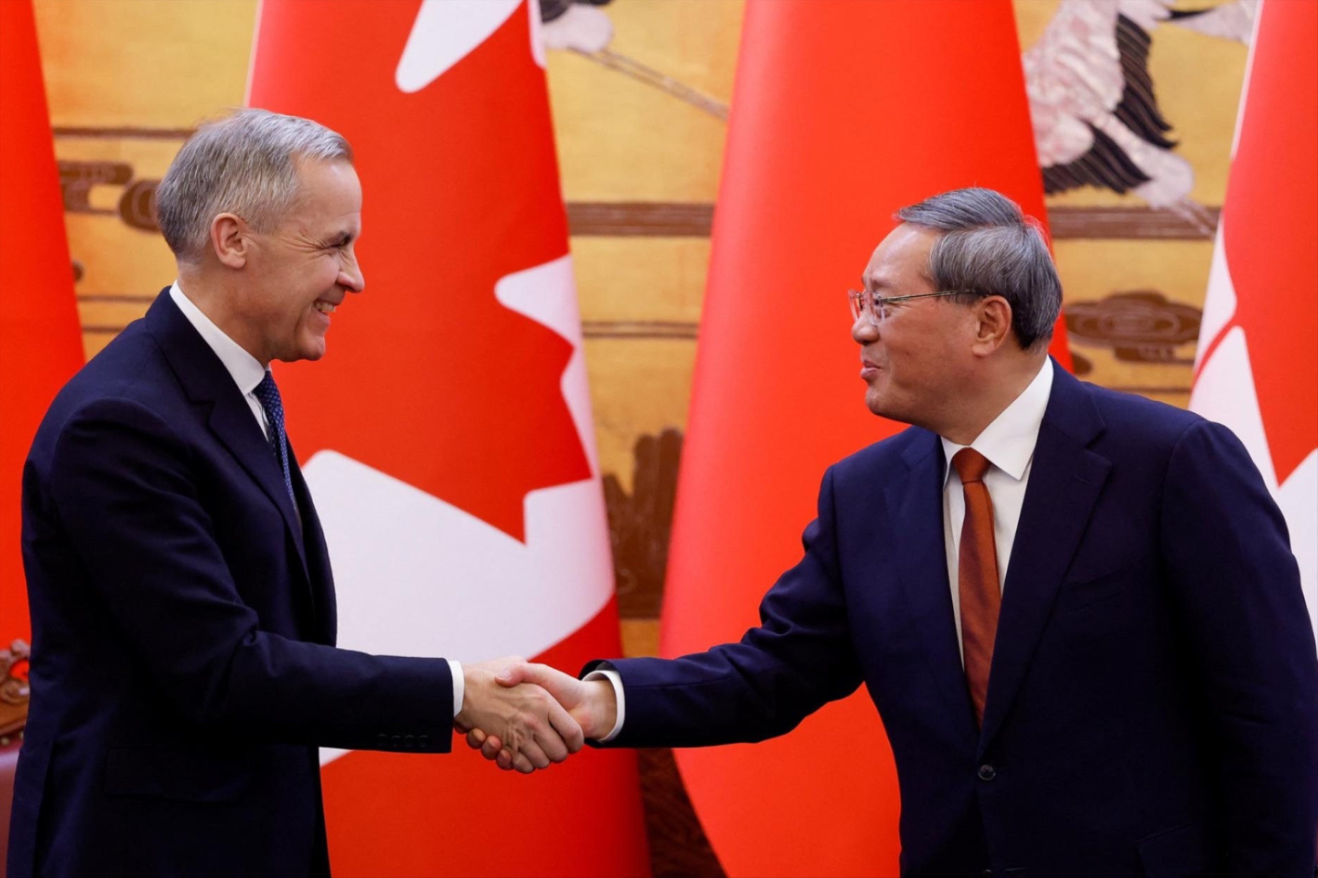 Canada's Prime Minister Mark Carney shakes hands with China's Premier Li Qiang at the end of the signing ceremony, January 15, 2026. 