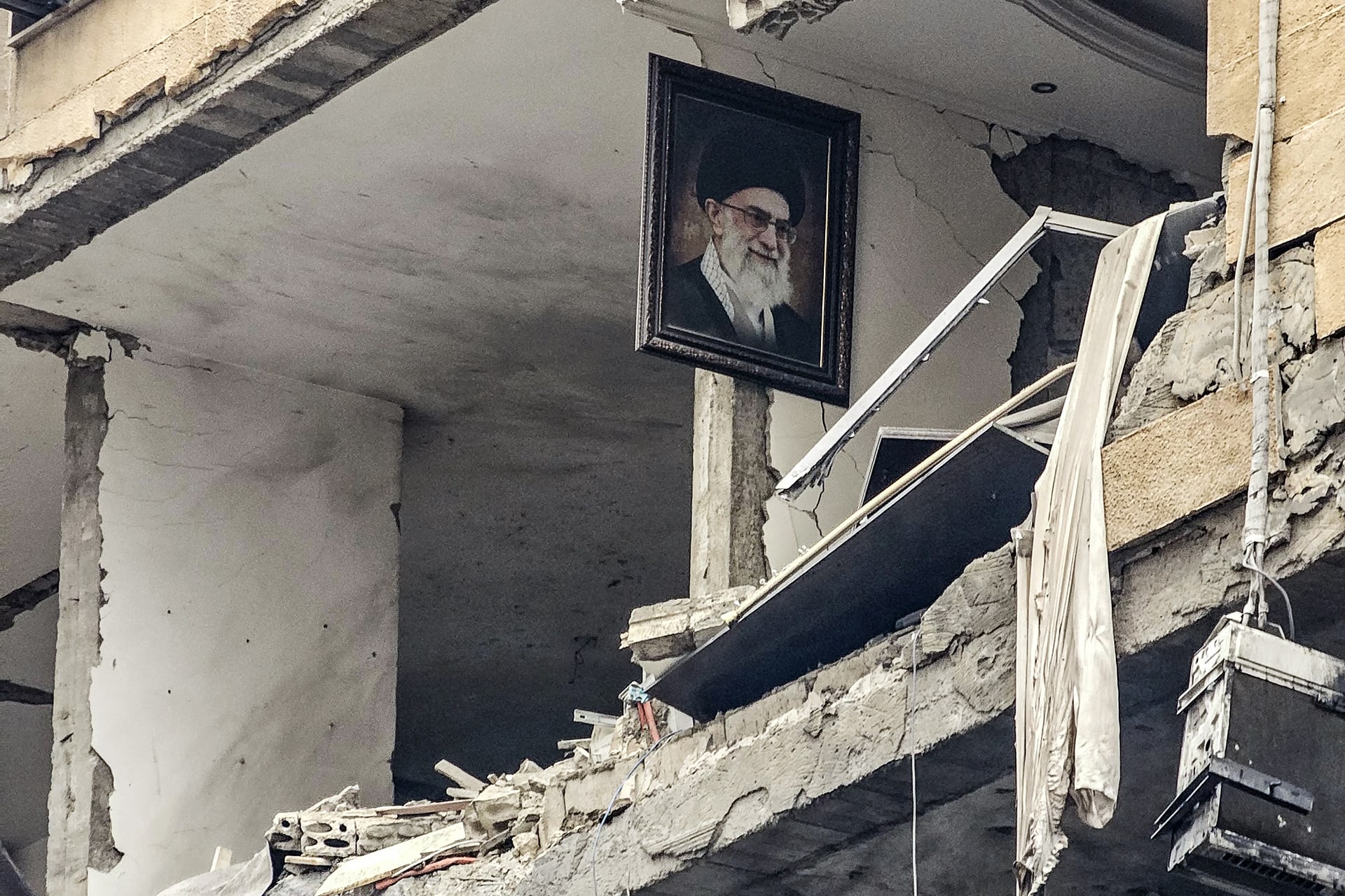 A portrait of Iran’s late Supreme Leader Ayatollah Ali Khamenei, who was killed in the opening salvo of the Iran war on February 28, is seen hanging on the wall of a destroyed building in Haret Hreik, Lebanon, on March 15, 2026. (AFP/Getty) 