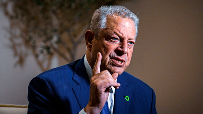 Former Vice President Al Gore clad in a brilliant blue suit holds up a finger as he speaks. 
