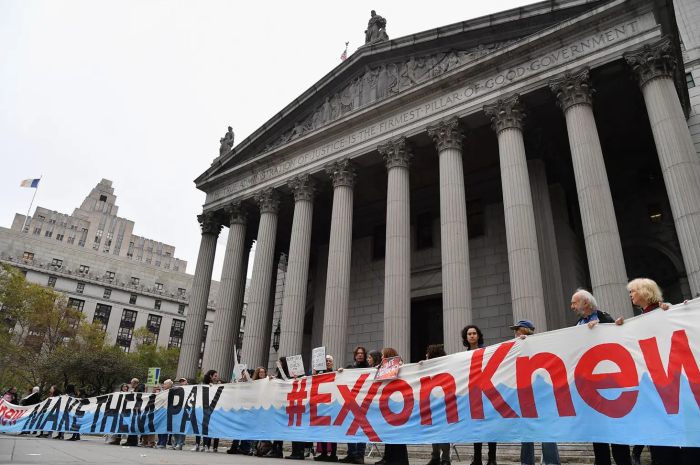 A group of climate advocates hold a long banner reading, 