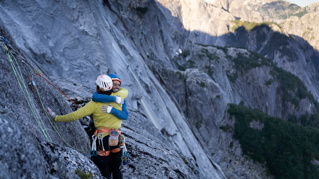 Two people hug on a climbing route.