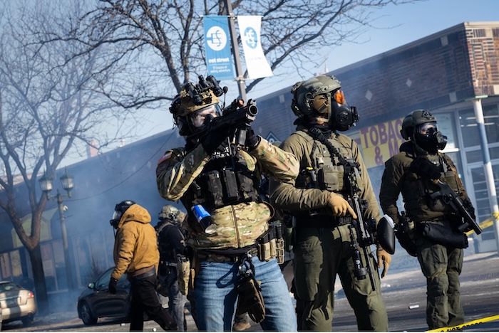 A border patrol agent aims a munition launcher at a crowd in Minneapolis after a federal officer shot and killed 37-year-old Alex Pretti on Saturday. Ben Hovland/Minnesota Public Radio via AP