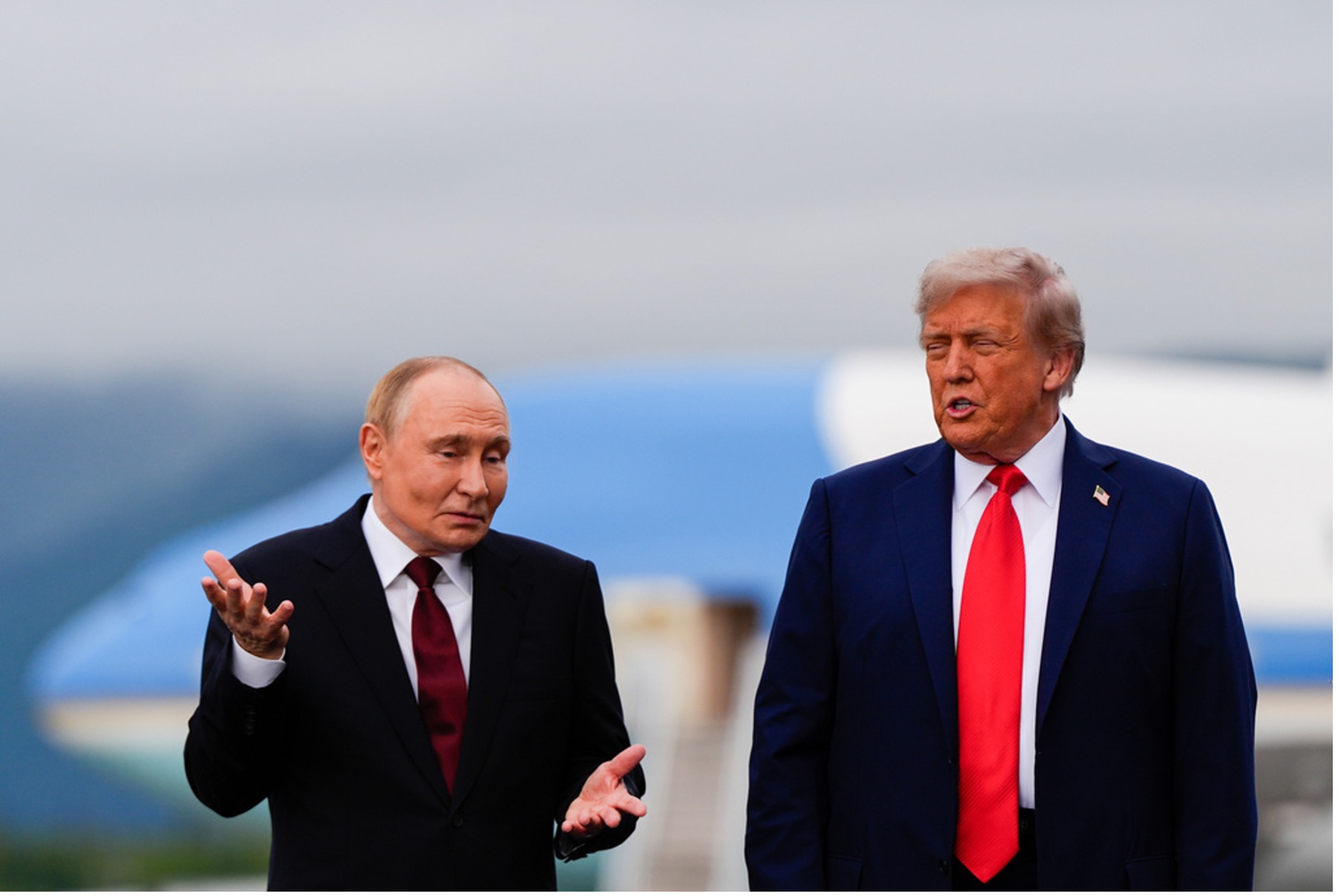 Donald Trump and Vladimir Putin stand side by side. Trump appears to be speaking, while Putin gestures with his right hand..
