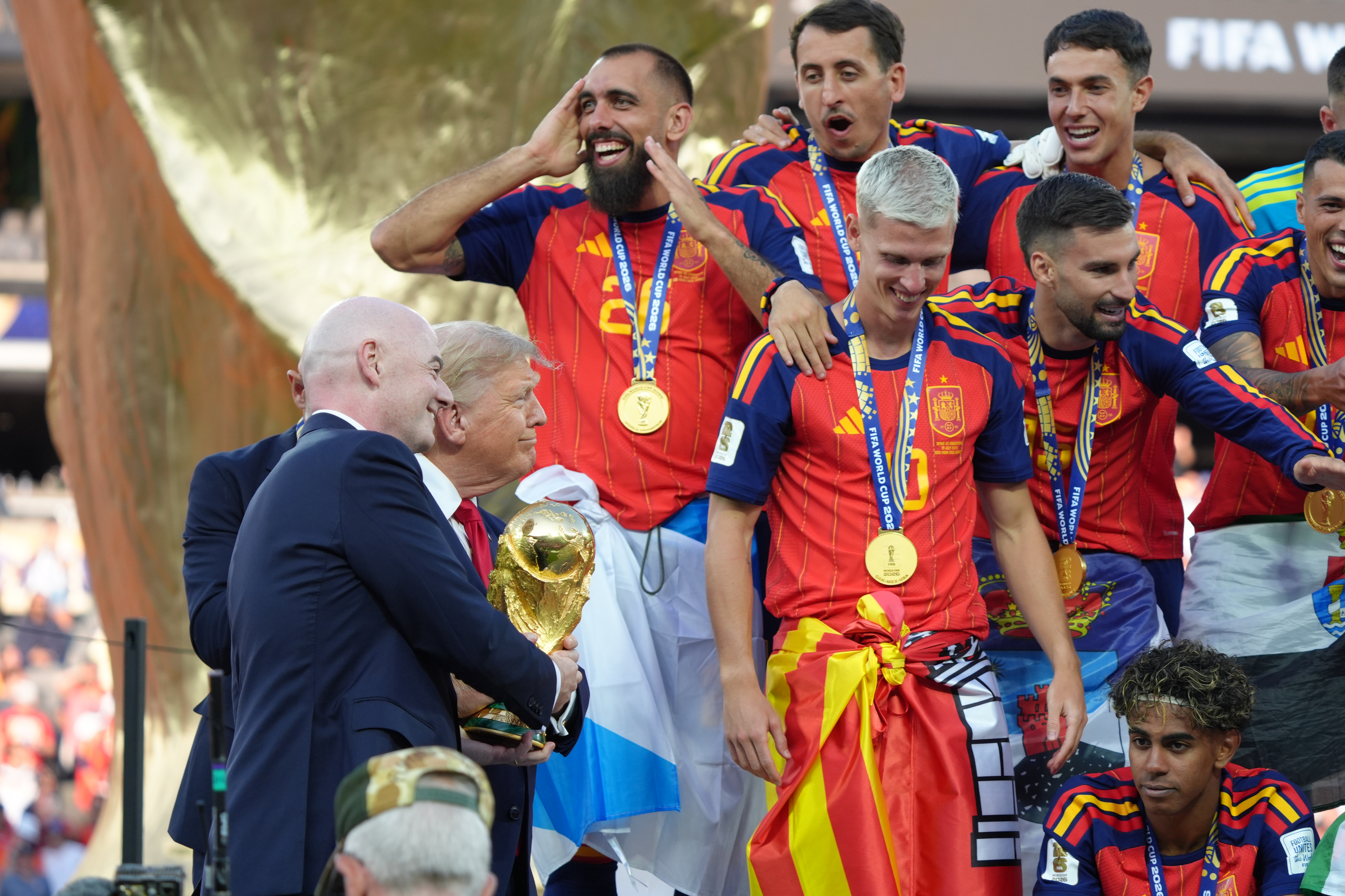 President Donald Trump and FIFA President Gianni Infantino hold the trophy as Spain teammates celebrate at the conclusion of the World Cup final soccer match between Spain and Argentina in East Rutherford, N.J., Sunday.
