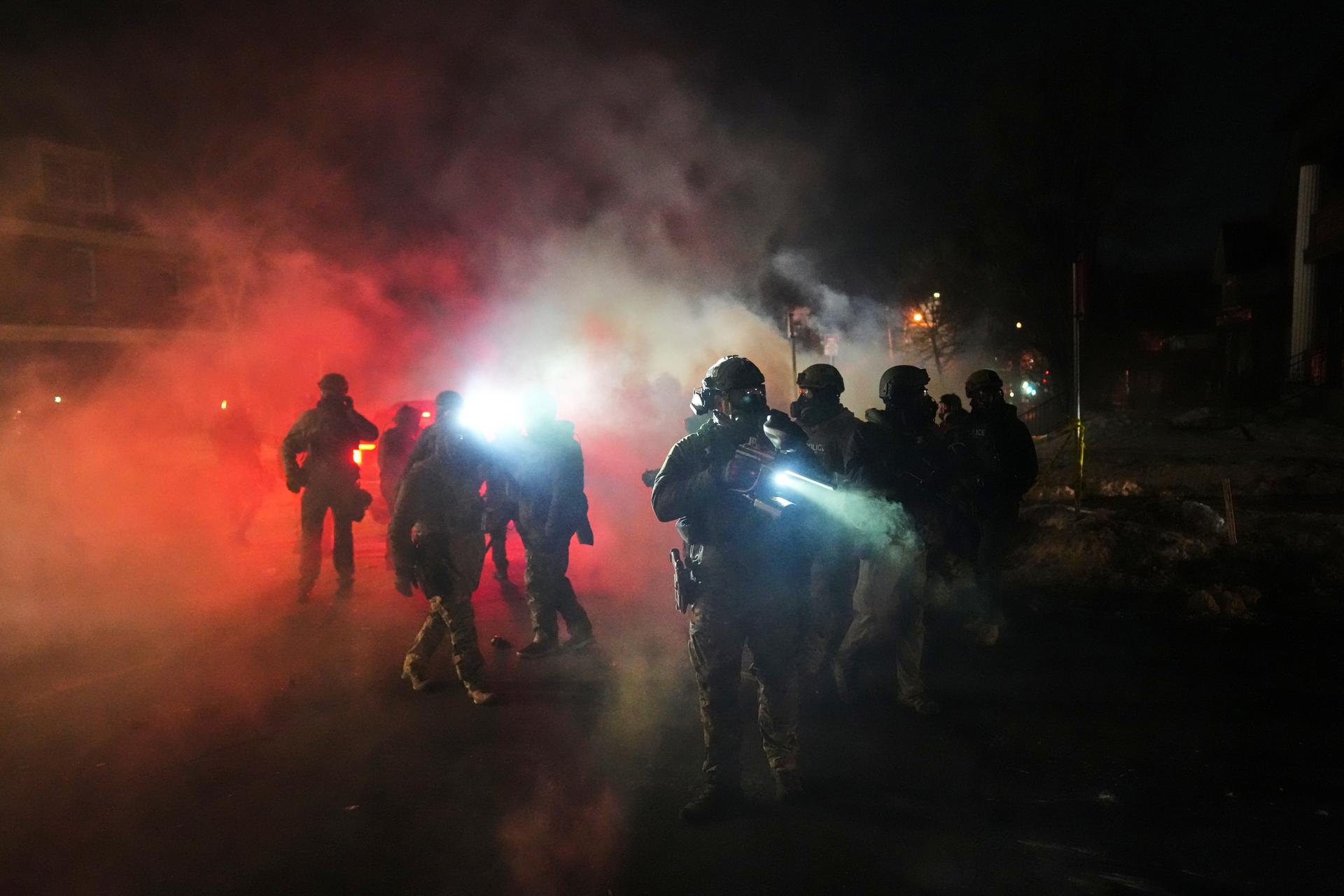 Law enforcement officers stand amid tear gas at the scene of a reported shooting Wednesday, in Minneapolis.