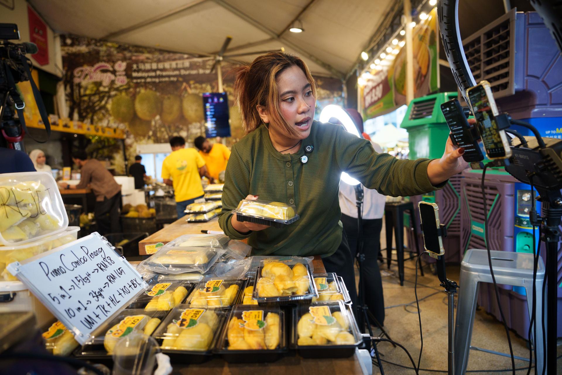 A worker livestreams while selling durians at a stall in Petaling Jaya, on the outskirts of Kuala Lumpur, Malaysia, in June.
