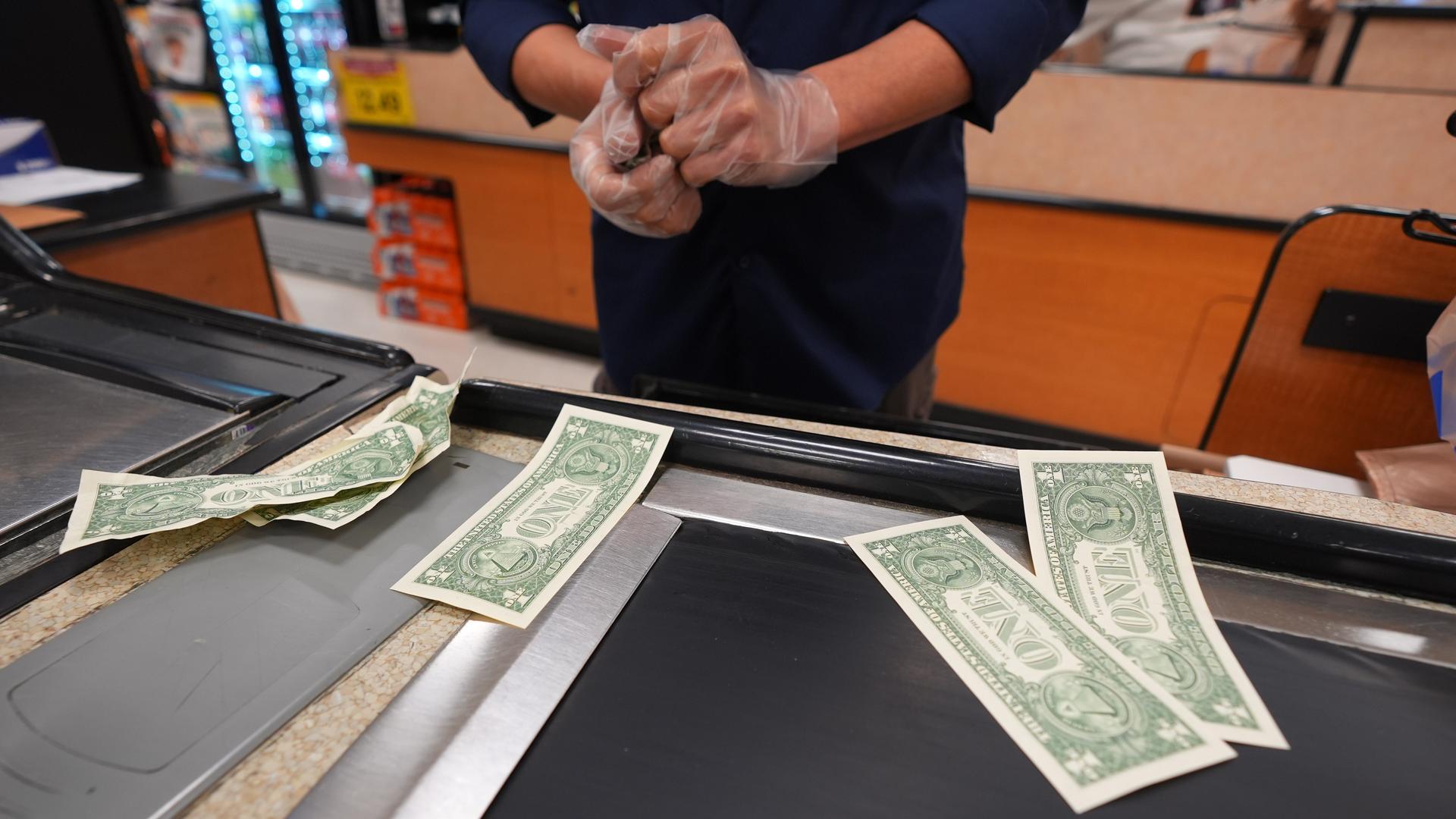 A grocery store cashier pauses while pulling dollar bills for their cash drawer in Dallas, in April. (AP Photo/LM Otero)
