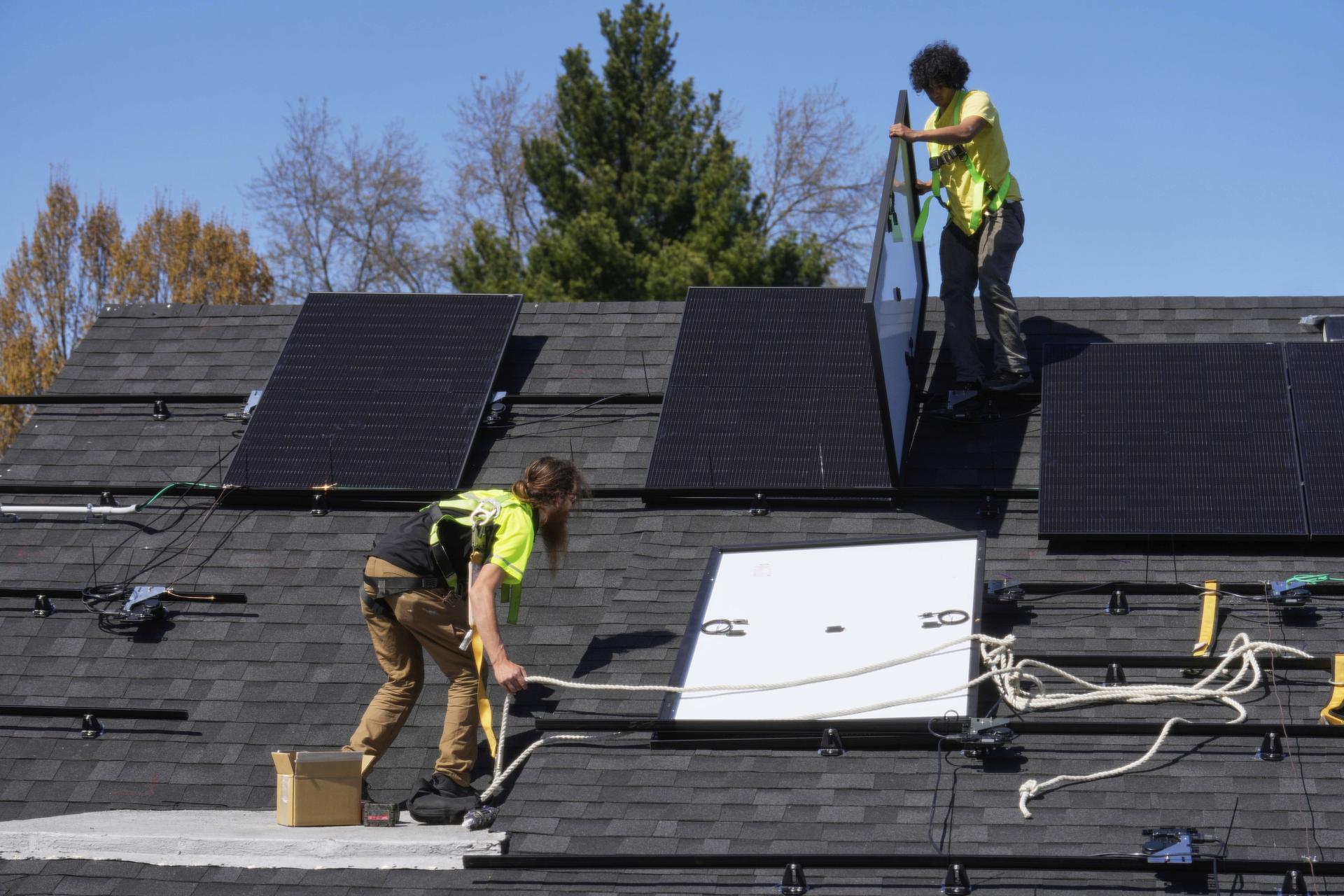 Theodore Tanczuk, left, and Brayan Santos, right, of solar installer YellowLite, put panels on the roof of a home in Lakewood, Ohio, April 16, 2025. (AP Photo/Sue Ogrocki).