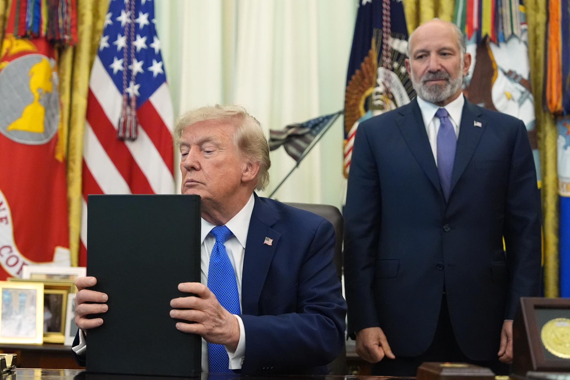 President Donald Trump listens before signing executive orders in the Oval Office of the White House, Aug. 6, in Washington, as Commerce Secretary Howard Lutnick watches.