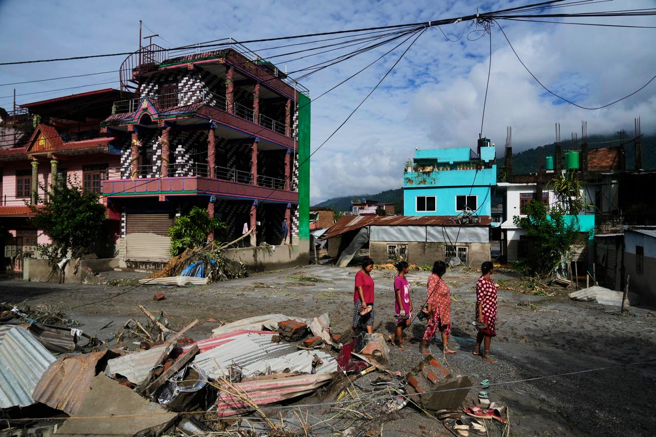 People walk past damage in the aftermath of flash floods in Devighat in the Nuwakot district in Nepal, Thursday.