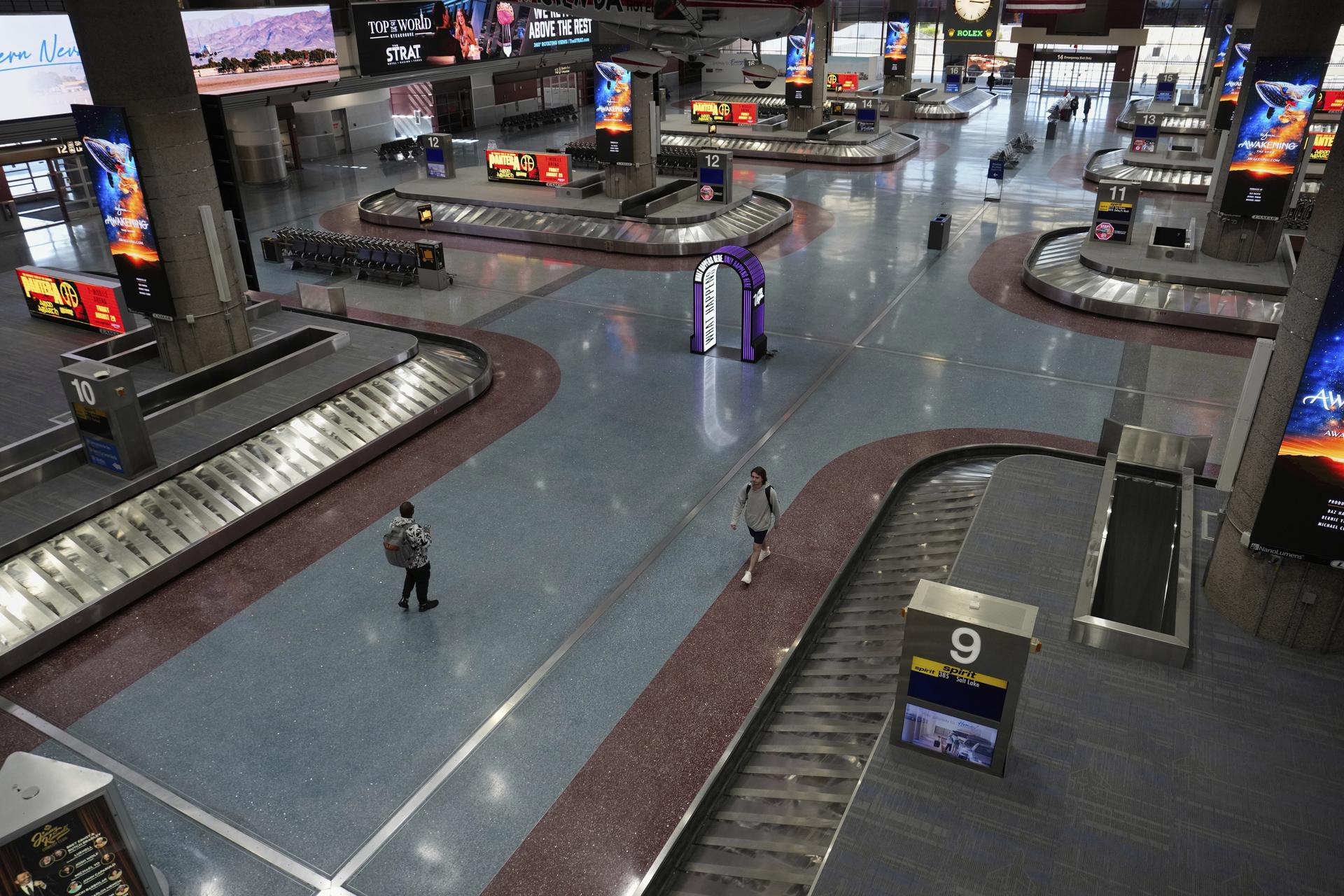 People walk through Harry Reid International Airport in Las Vegas on Friday. (AP Photo/John Locher)