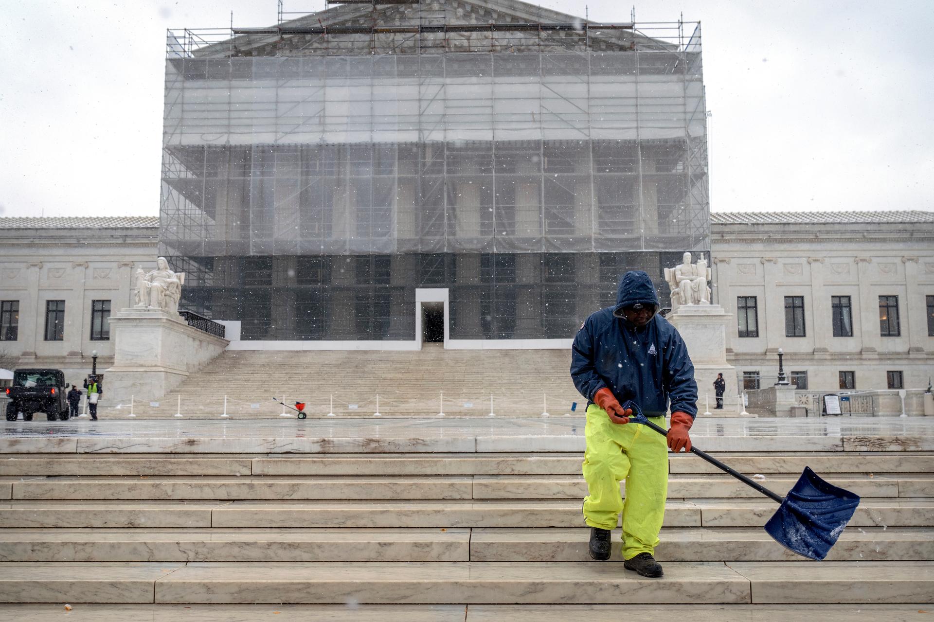 A worker shovels snow and ice in front of the Supreme Court building on Friday. (AP Photo/Mark Schiefelbein)