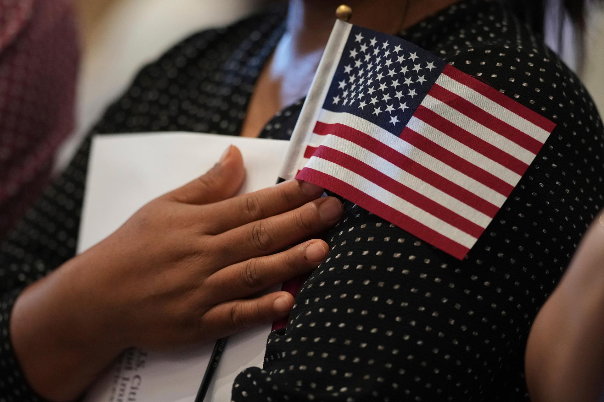 A woman clutches a U.S. flag as she and applicants from other countries prepare to take the oath of citizenship in San Antonio on July 3. (AP Photo/Eric Gay)