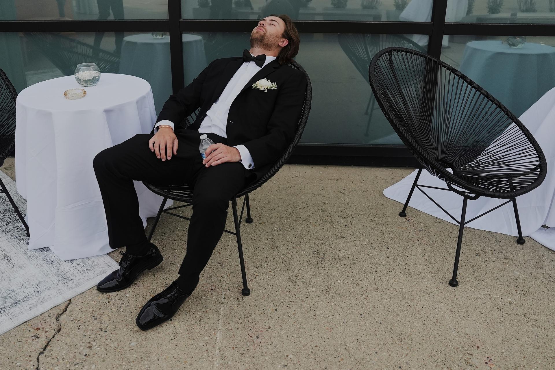 A groomsman takes a break after finishing bridal party photos at a wedding on Aug. 23 in Newtown, Ohio. (AP Photo/Joshua A. Bickel)