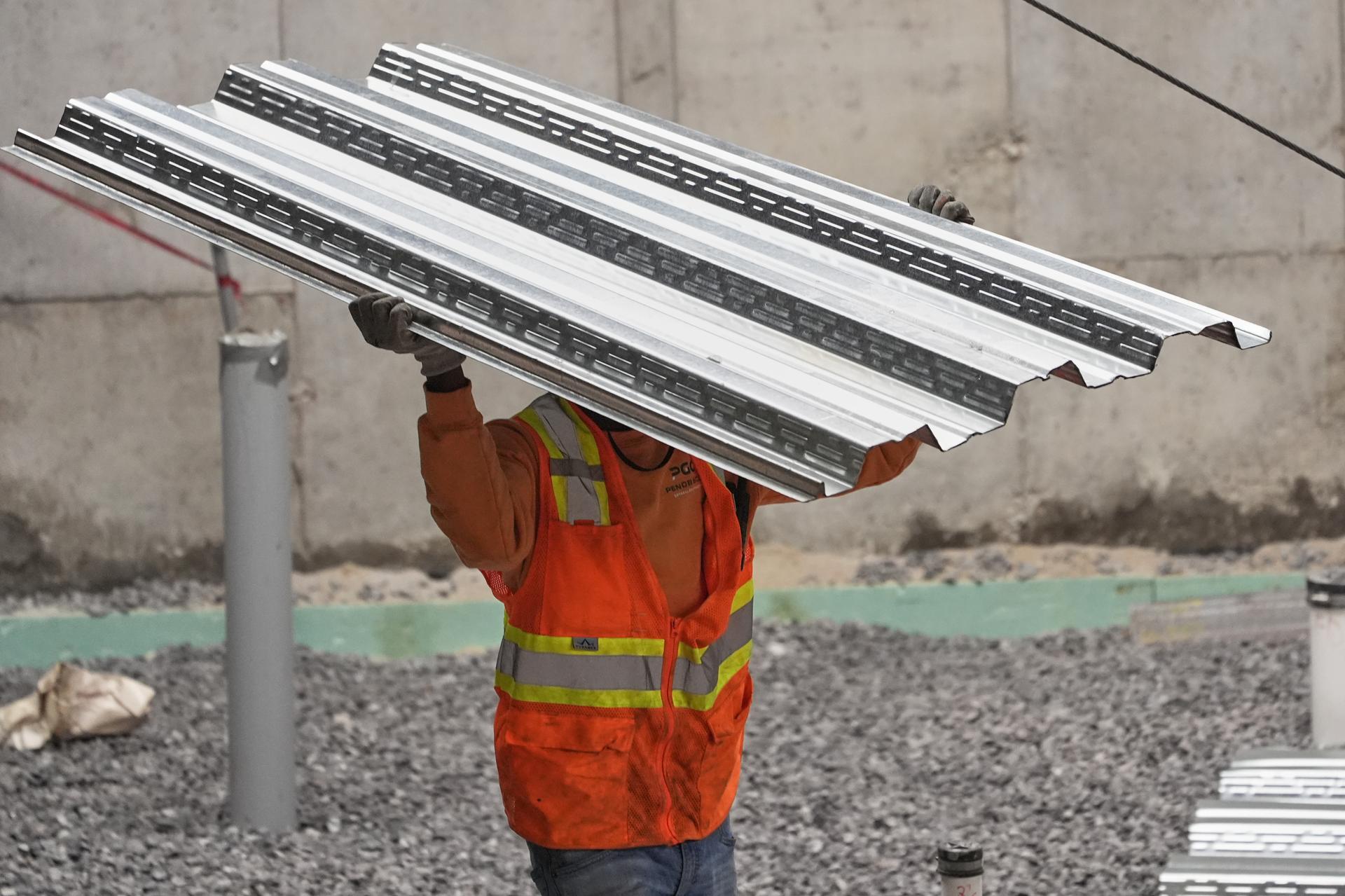 A construction worker carries steel decking at a construction site in Portland, Maine, in July. (AP Photo/Robert F. Bukaty) 