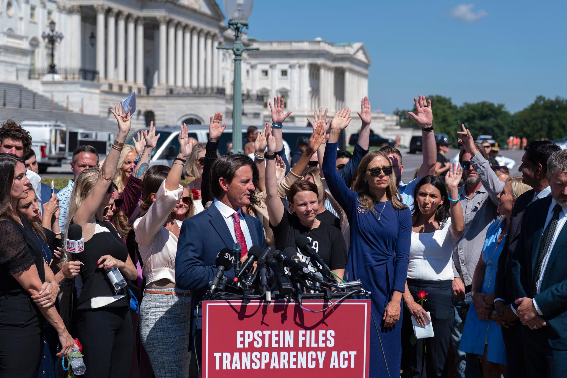 Attendees raise their hands to press congress to release the Jeffrey Epstein files during a news conference at the U.S. Capitol, Wednesday in Washington.
