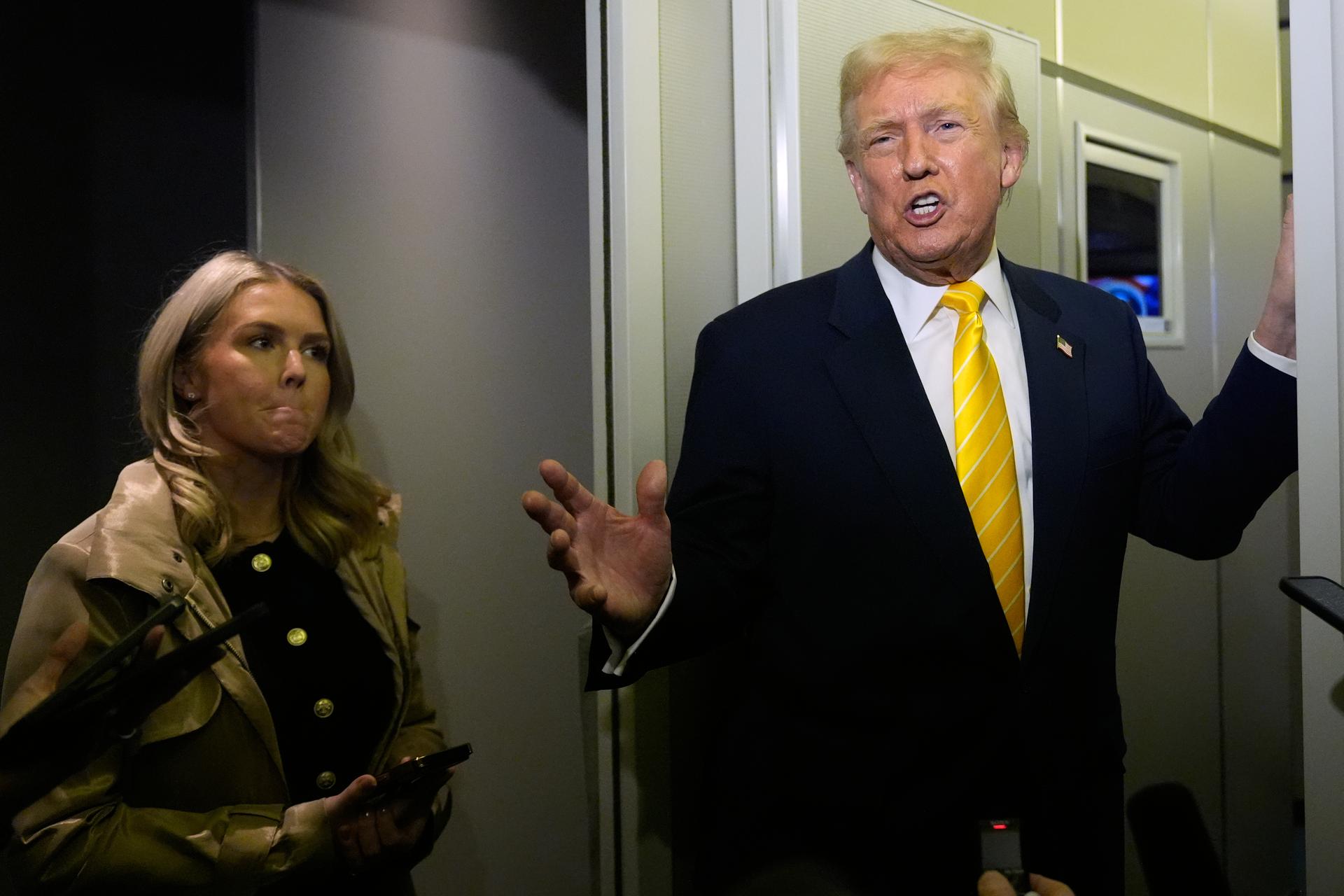 President Donald Trump speaks to reporters on Air Force One on his way to his Mar-a-Lago estate in Palm Beach, Fla., Friday, as White House press secretary Karoline Leavitt listens.