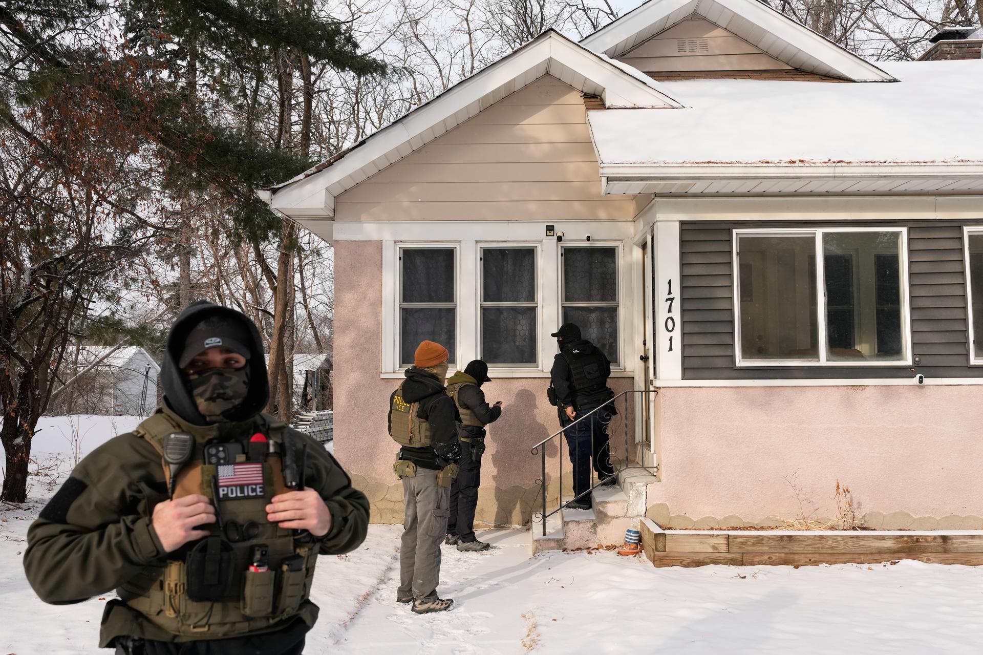 Federal law enforcement officers knock on the door of a house on Sunday in St. Paul, Minn.