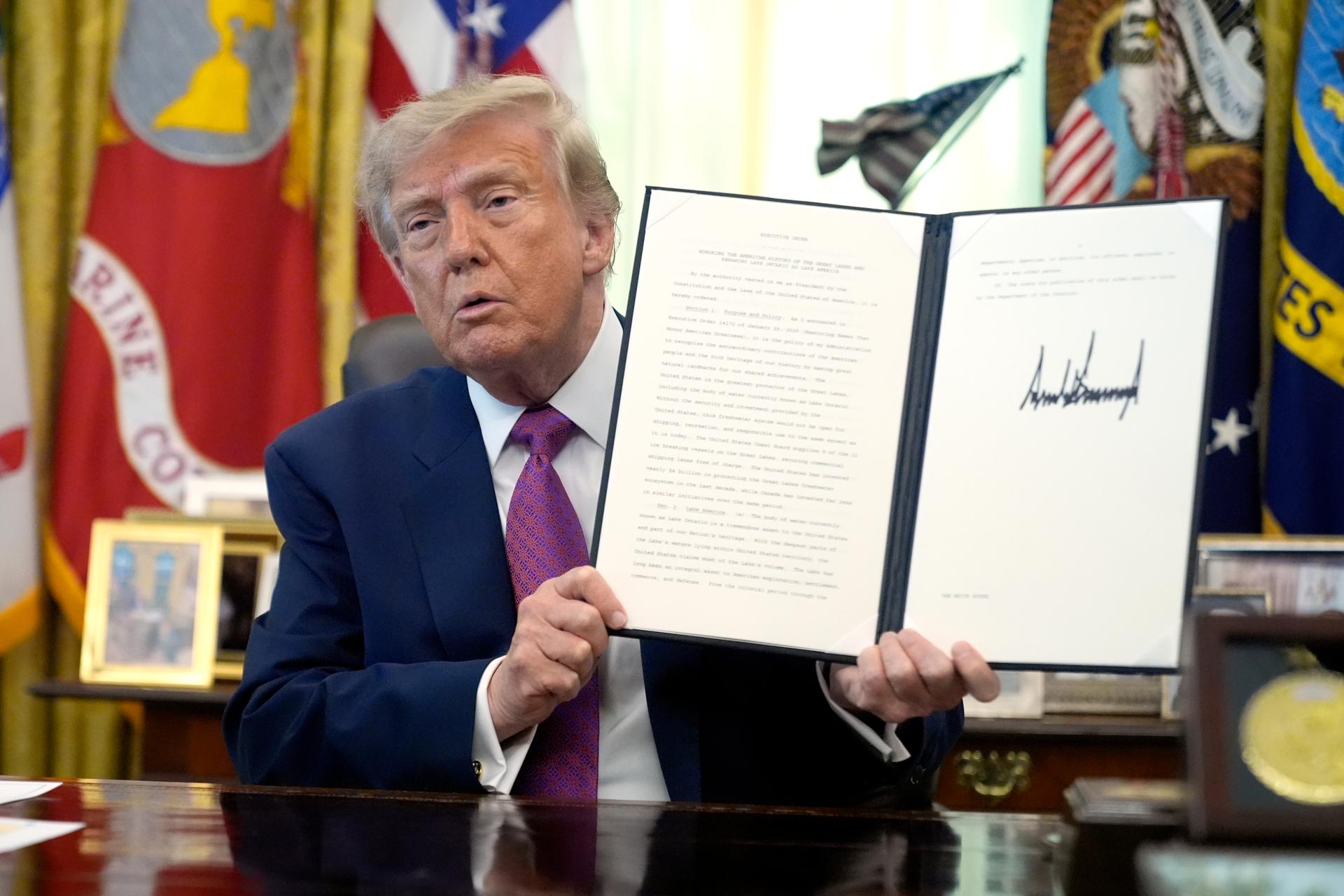 President Donald Trump holds up a signed executive order in the Oval Office of the White House, Thursday, in Washington. 
