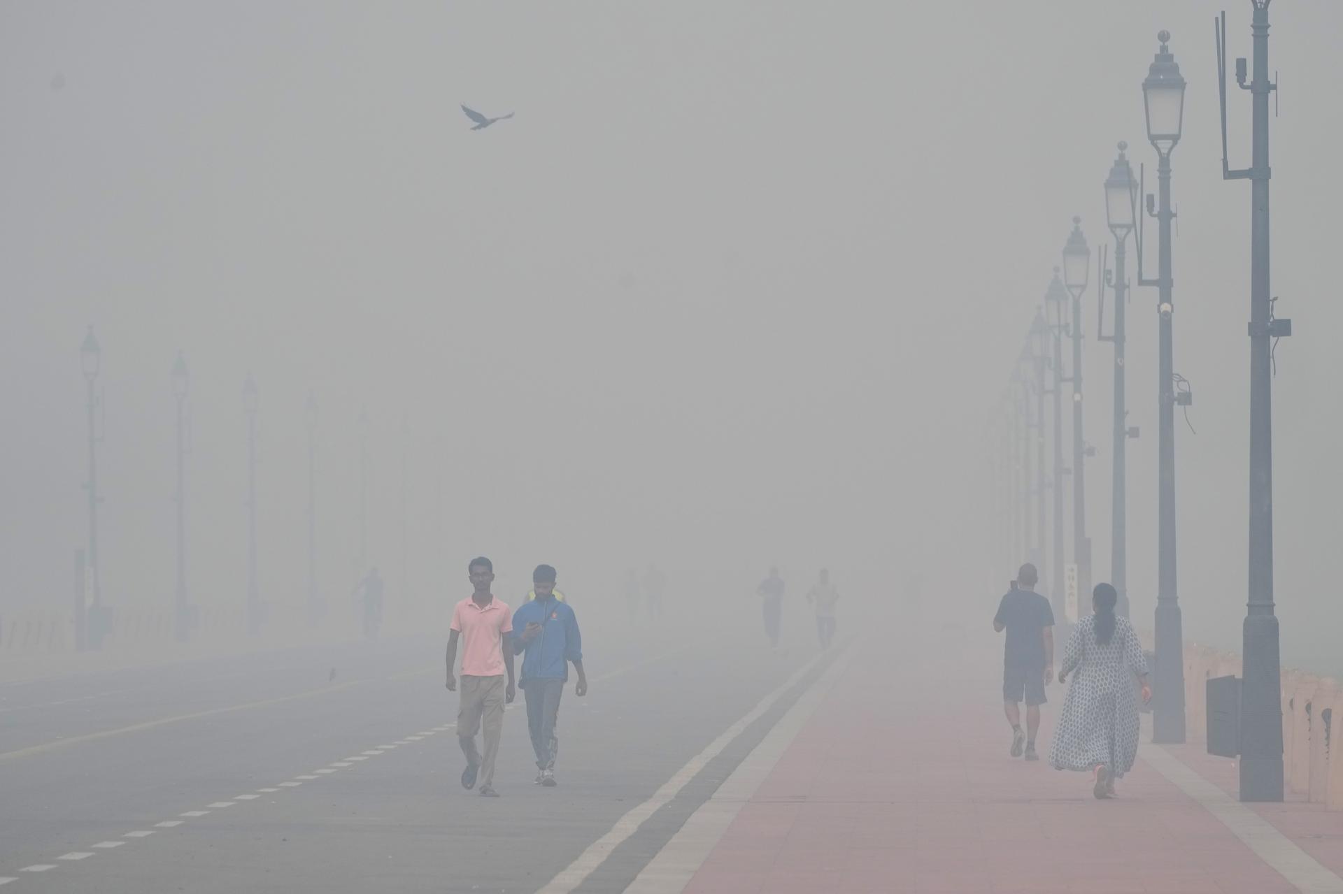 People walk in the morning near the India Gate monument in New Delhi, India, on Tuesday. (AP Photo/Manish Swarup)