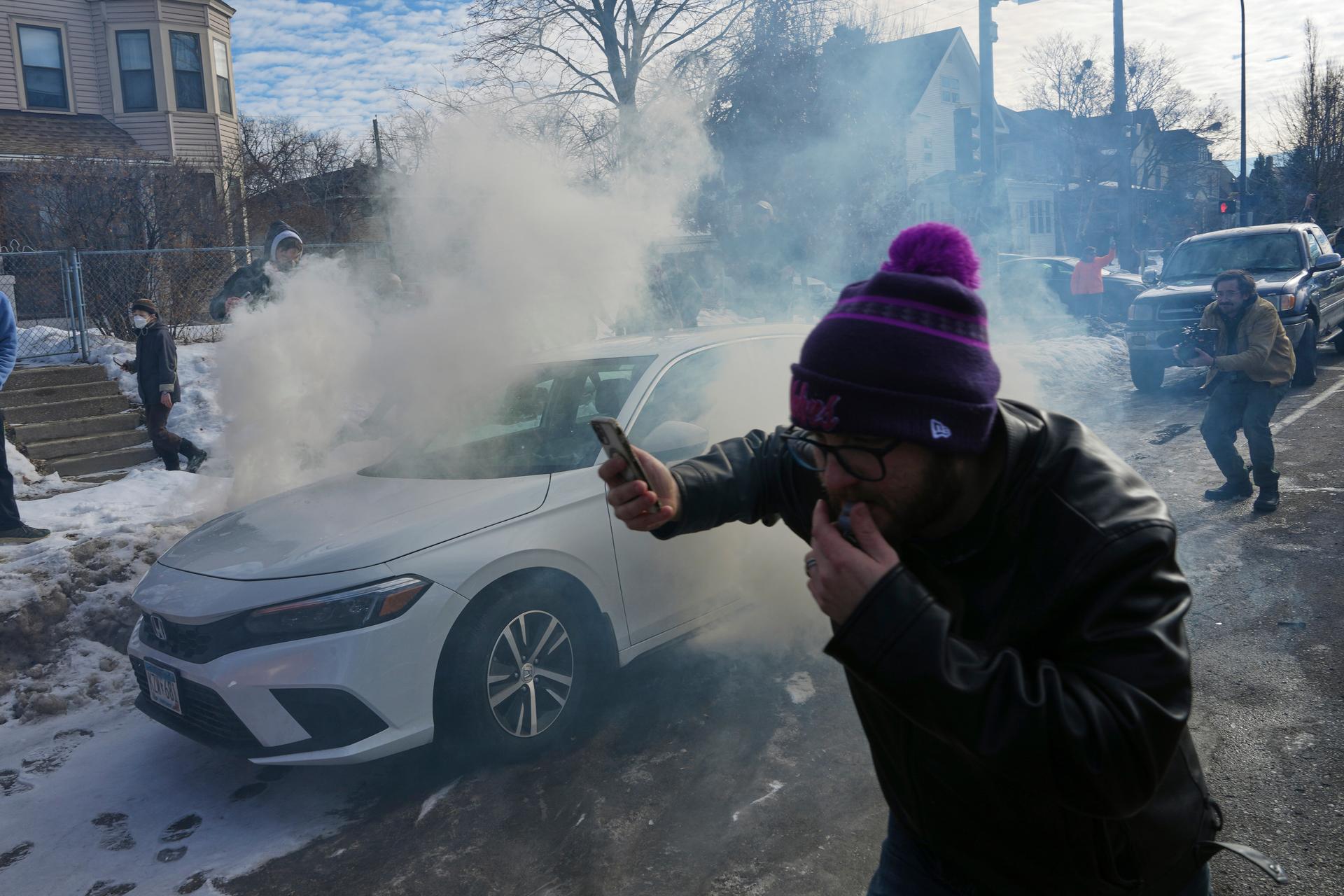 Protesters try to avoid tear gas dispersed by federal agents, Monday, in Minneapolis.
