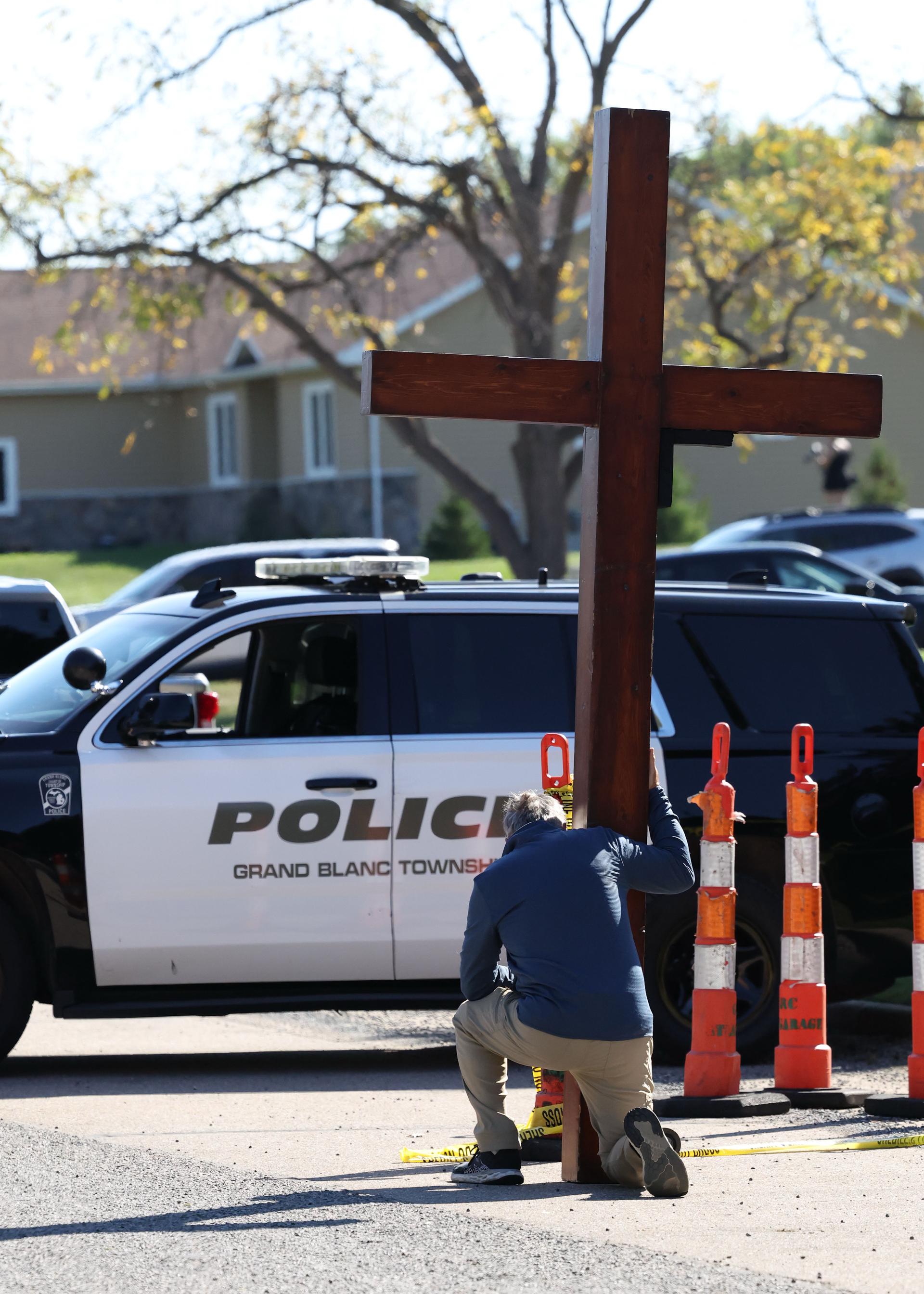 Dan Beazley holds his 10-foot-cross and prays near the Church of Jesus Christ of Latter-day Saints, in Grand Blanc Township, Mich., on Monday. (AP Photo/Carlos Osorio)