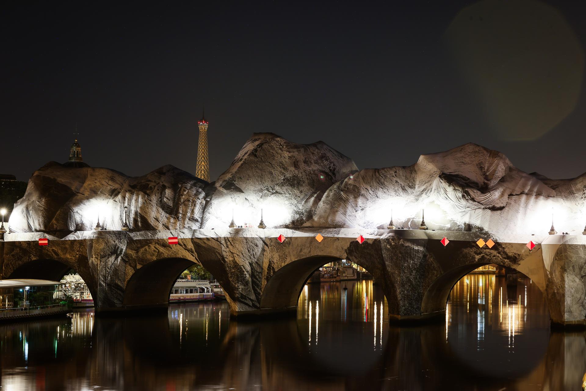 Inflation of the artwork “The Pont Neuf Cave” by French street artist JR on the Pont Neuf bridge, with the Eiffel Tower behind it, Thursday, in Paris. 
