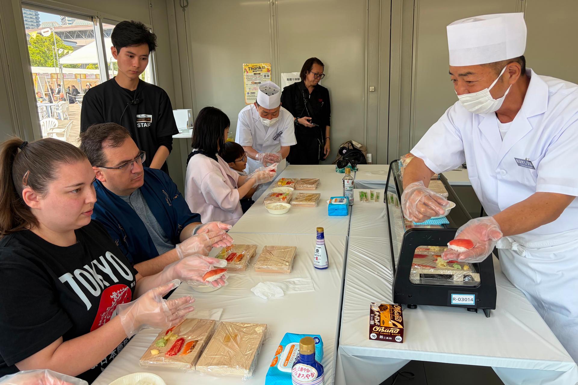 Brittany Nevins and her husband Kevin, both from Erlander, Ky., try making sushi for the first time with a sushi master in Tokyo, on May 15.