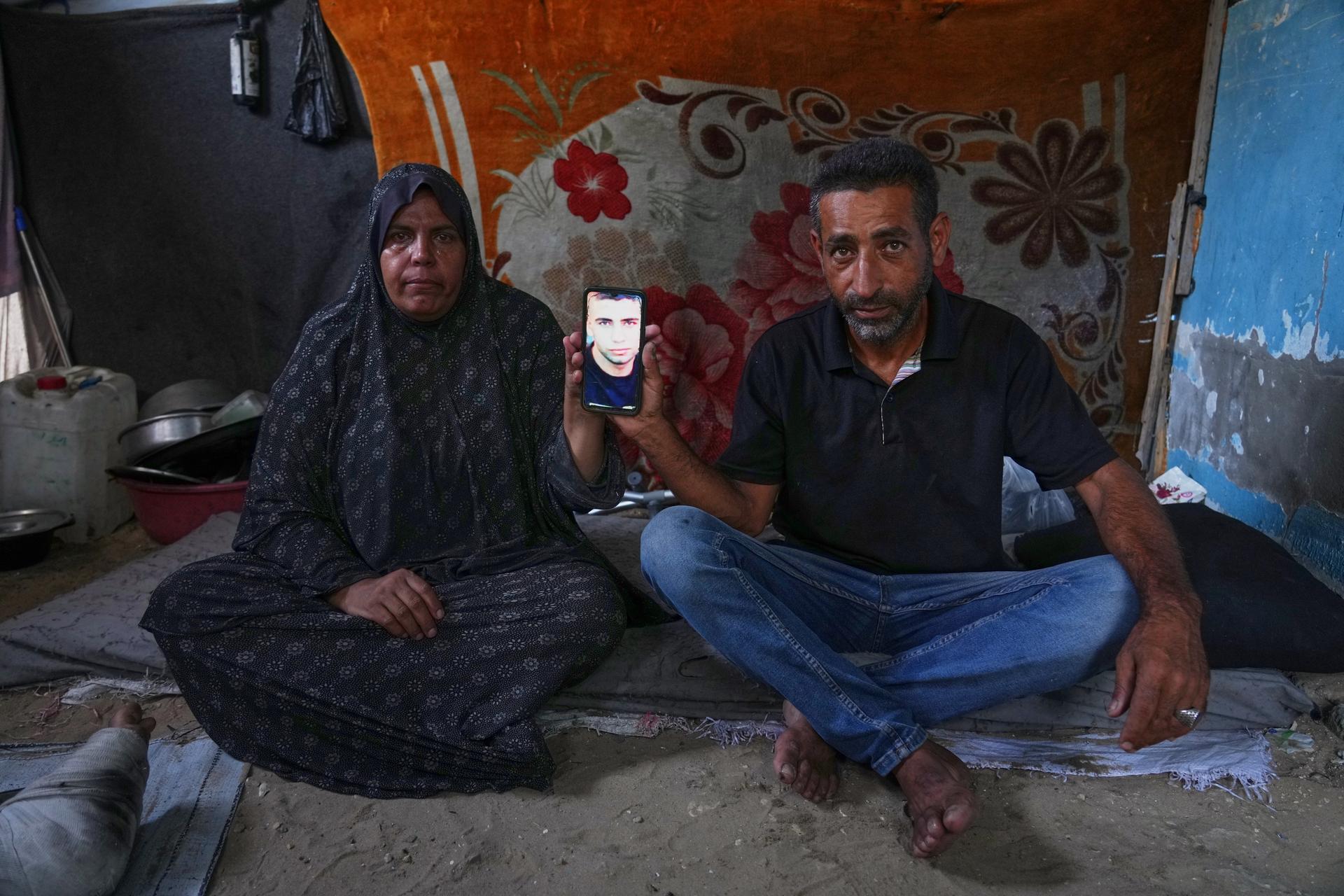 Mohammad and Tahani al-Najjar hold a cellphone showing a picture of their son, Ahmad, at their family's tent in Muwasi, along Gaza's southern coast, in February. (AP Photo/Jehad Alshrafi)