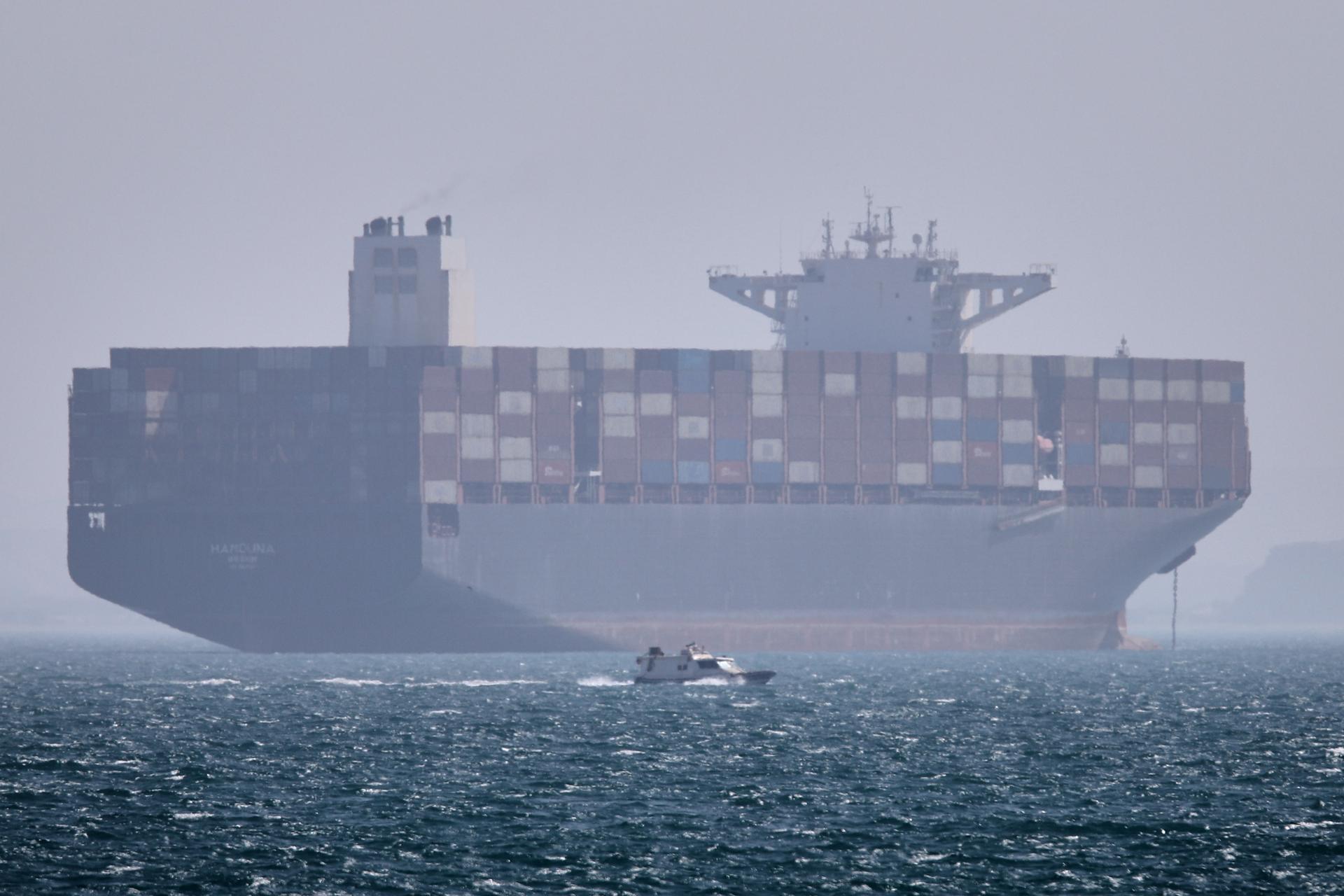 A container ship sits at anchor as a small motorboat passes in the foreground in the Strait of Hormuz off Bandar Abbas, Iran, Saturday.