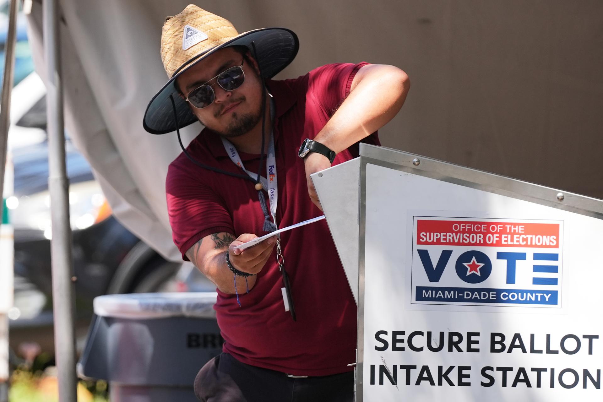   An election worker places a vote-by-mail ballot into a secure bin at the Miami-Dade County Supervisor of Elections Office during the primary election in Doral, Fla., Aug. 18.
