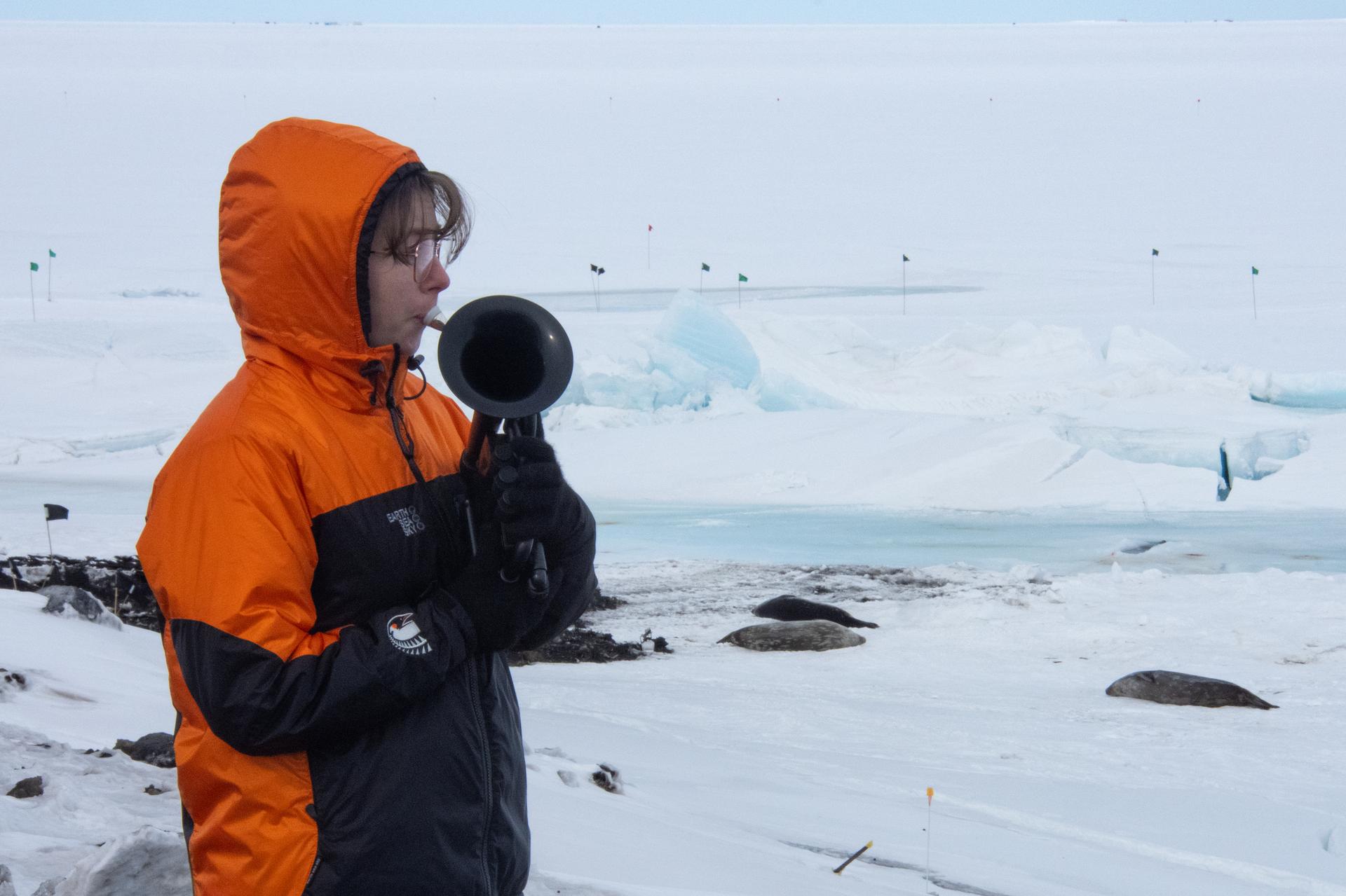 In this photo provided by Antarctica New Zealand, Natalie Paine plays a plastic French horn at Scott Base in Antarctica, Sunday.
