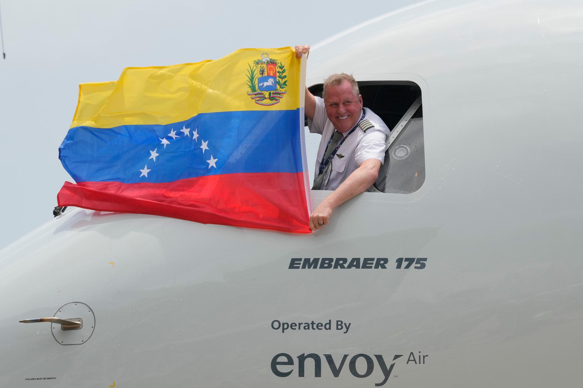 The pilot of a U.S. aircraft holds a Venezuelan flag from the cockpit window after landing at Simon Bolivar International Airport in Maiquetia, Venezuela, on Thursday. (AP Photo/Ariana Cubillos)