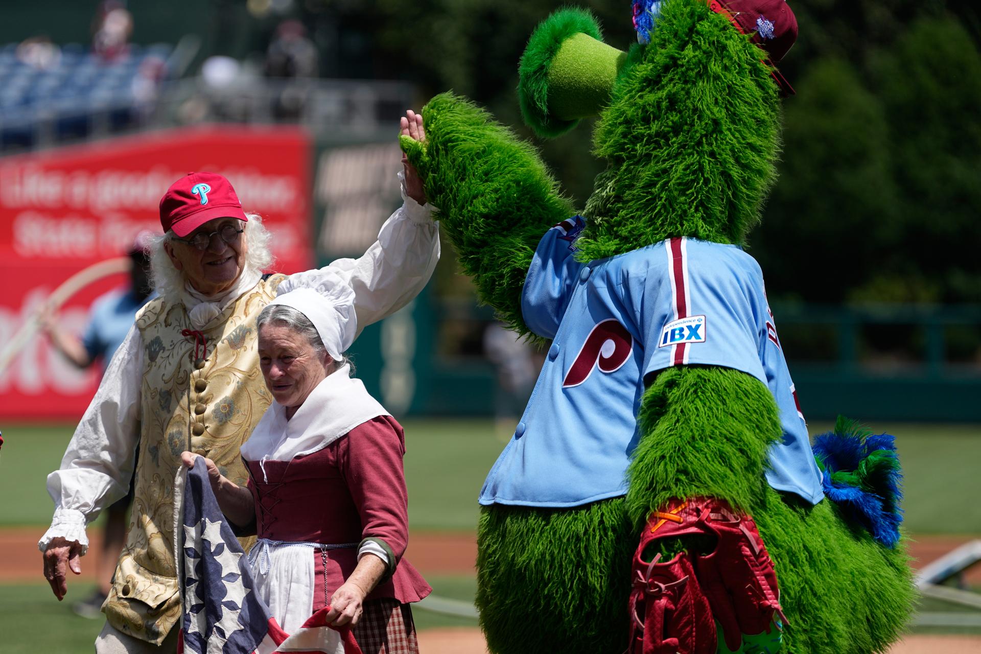 Bill Robling as Benjamin Franklin, left, and Carol Spacht as Betsy Ross, center, greet the Philadelphia Phillies mascot, the Phillie Phanatic, before a baseball game on July 2 in Philadelphia.