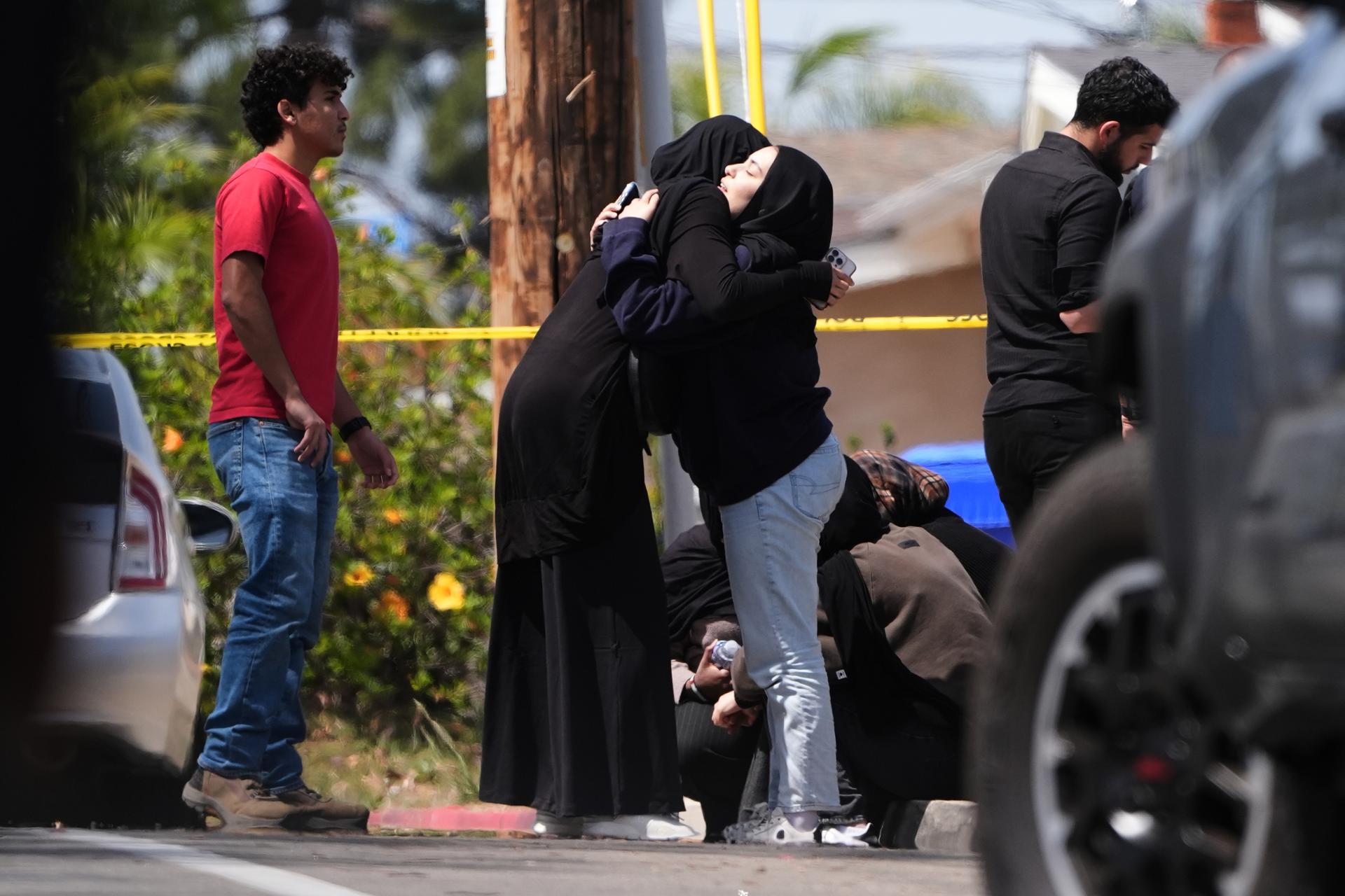 People embrace near the scene of a shooting outside the Islamic Center of San Diego Monday.
