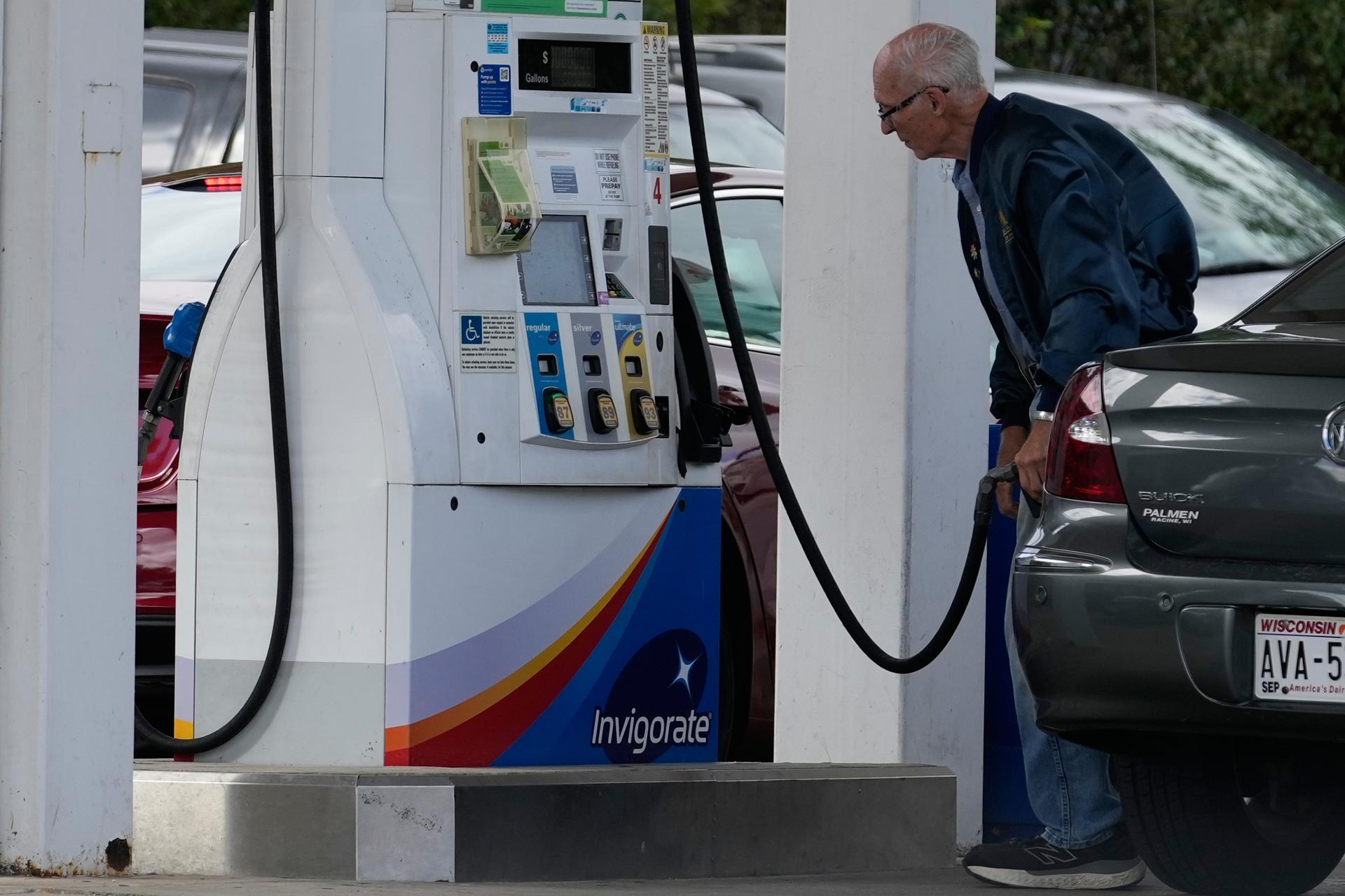 A customer checks gas price while he fills up his vehicle’s tank at a gas station in Racine, Wis., in September. 