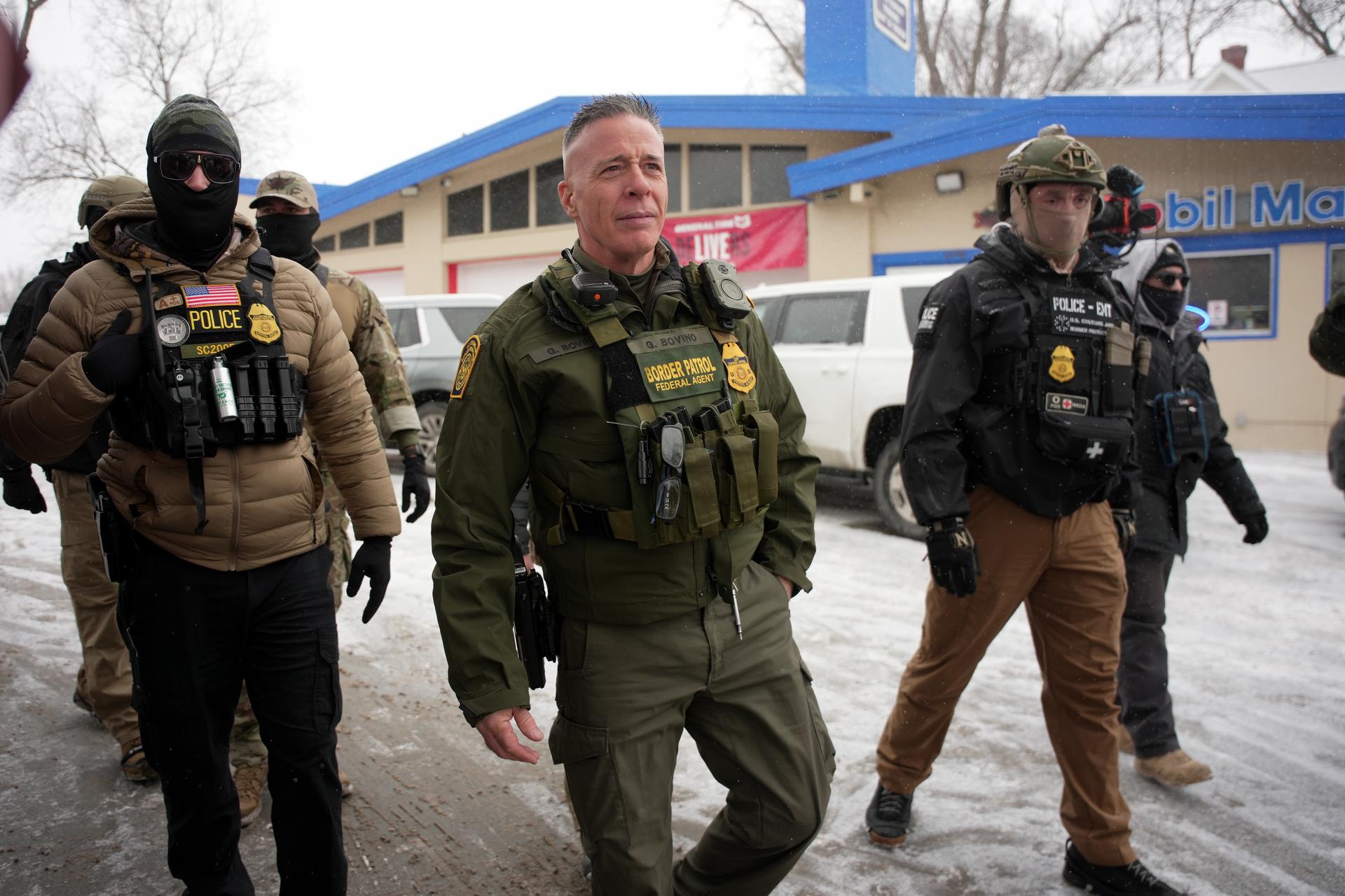 U.S. Border Patrol Cmdr. Gregory Bovino walks with federal agents outside a convenience store on Wednesday, in Minneapolis.